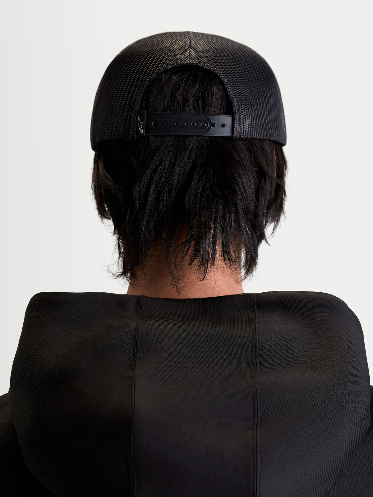 Alpinestars Gravel Trucker pet, sportswear snapback-pet, unisex, zwart, achteraanzicht op model met ademende poly-mesh achterkant en verstelbare snapback-sluiting