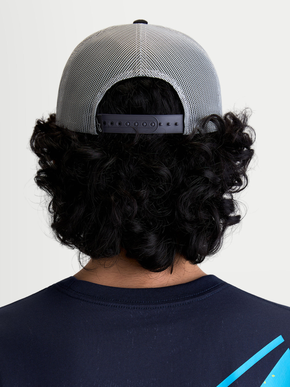 Alpinestars Gravel Trucker pet, casual sportswear truckerpet, achterzicht op model met ademende poly-mesh achterkant en verstelbare snapback-sluiting voor een persoonlijke pasvorm, grijs en zwart.