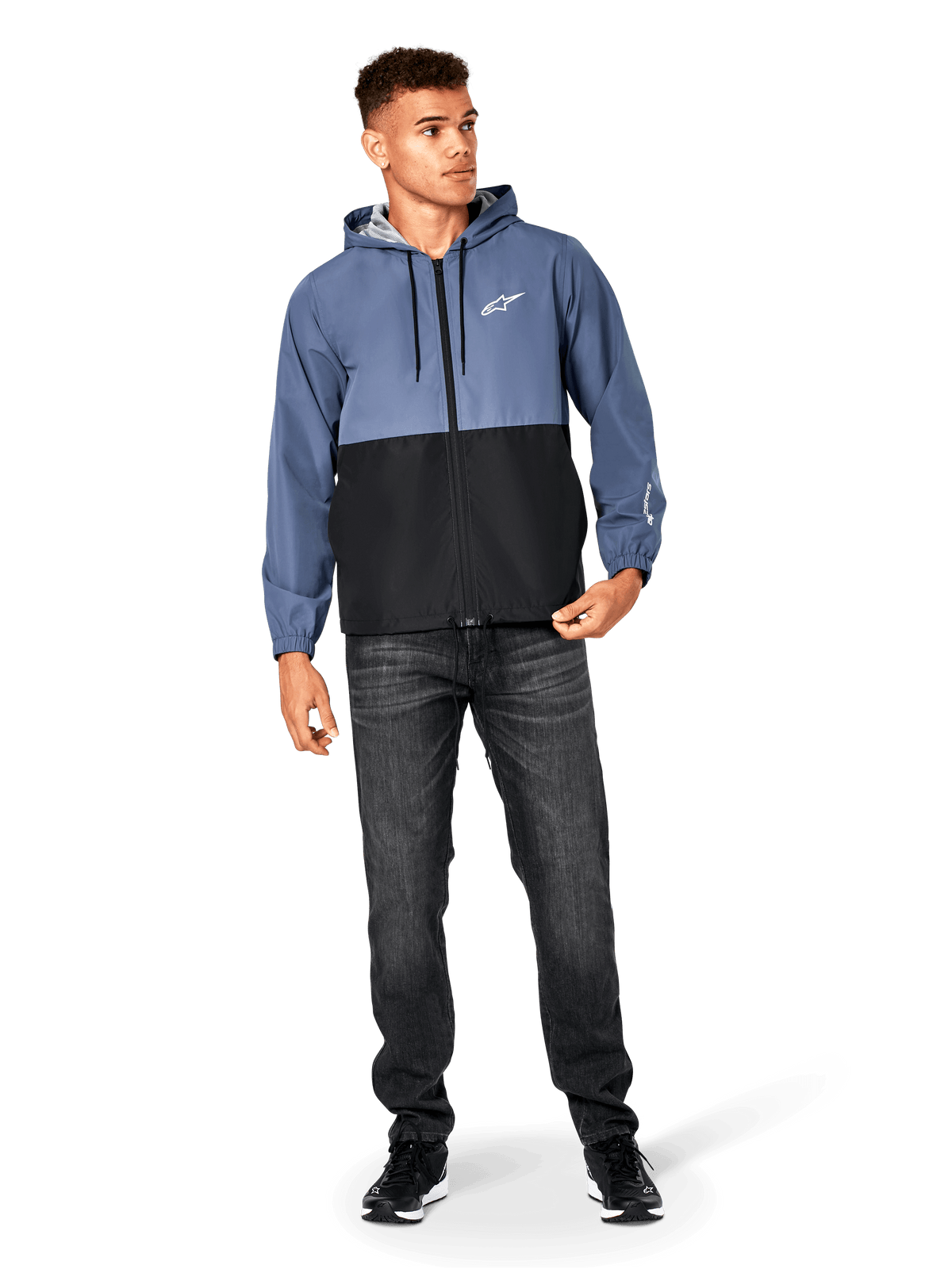 Alpinestars Speeder Windbreaker jas, Slate Blue en zwart, lichtgewicht jack met capuchon en mesh voering, wit sterlogo op de borst, gedragen met zwarte jeans en sneakers, casual motorsport streetwear design.
