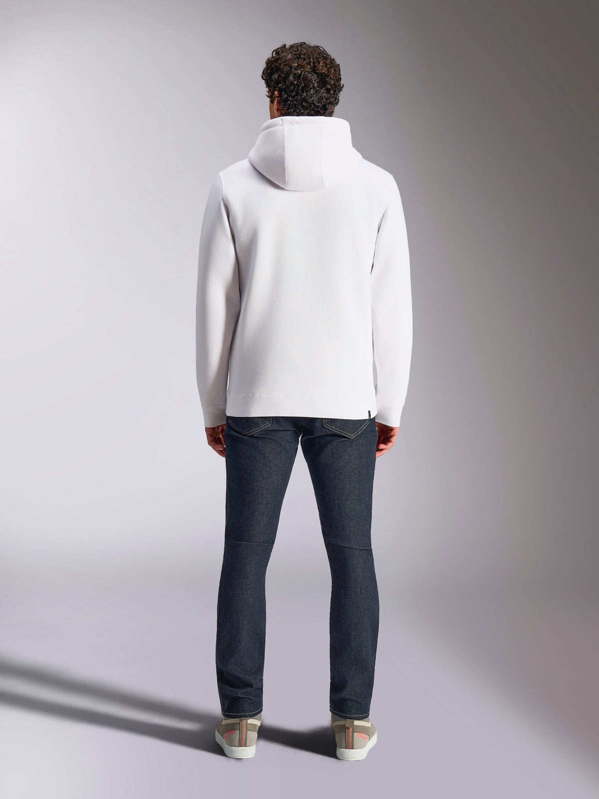 Alpinestars Blaze V3 Hoodie, white casual sportswear hoodie, back view of pullover fleece, clean design with ribbed cuffs and hem, styled with dark blue jeans and sneakers, modern motorsport-inspired lifestyle wear