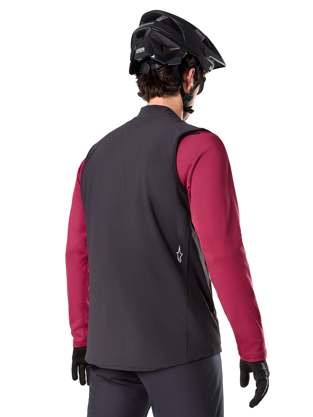 Alpinestars A-Dura Thermovest, zwart, achteraanzicht, gedragen over een bordeauxrode jersey met lange mouwen, met een zwarte mountainbikehelm en handschoenen, lichtgewicht geïsoleerde fietskleding voor off-road rijden