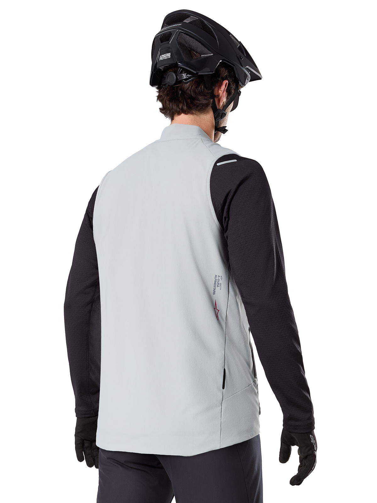 Alpinestars A-Dura Thermisch Vest, Titanium Grijs, achteraanzicht van model met zwart jersey met lange mouwen en MTB-helm, minimalistisch ontwerp met klein rood sterlogo op de rug, lichtgewicht geïsoleerde fietsgilet voor off-road rijden