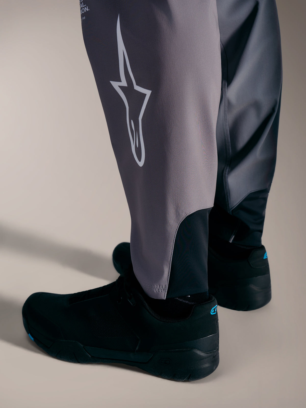 Grijze A-Supra Elite-broek met wit Astars-logo en stretchmanchetten voor prestatiegerichte MTB-races.