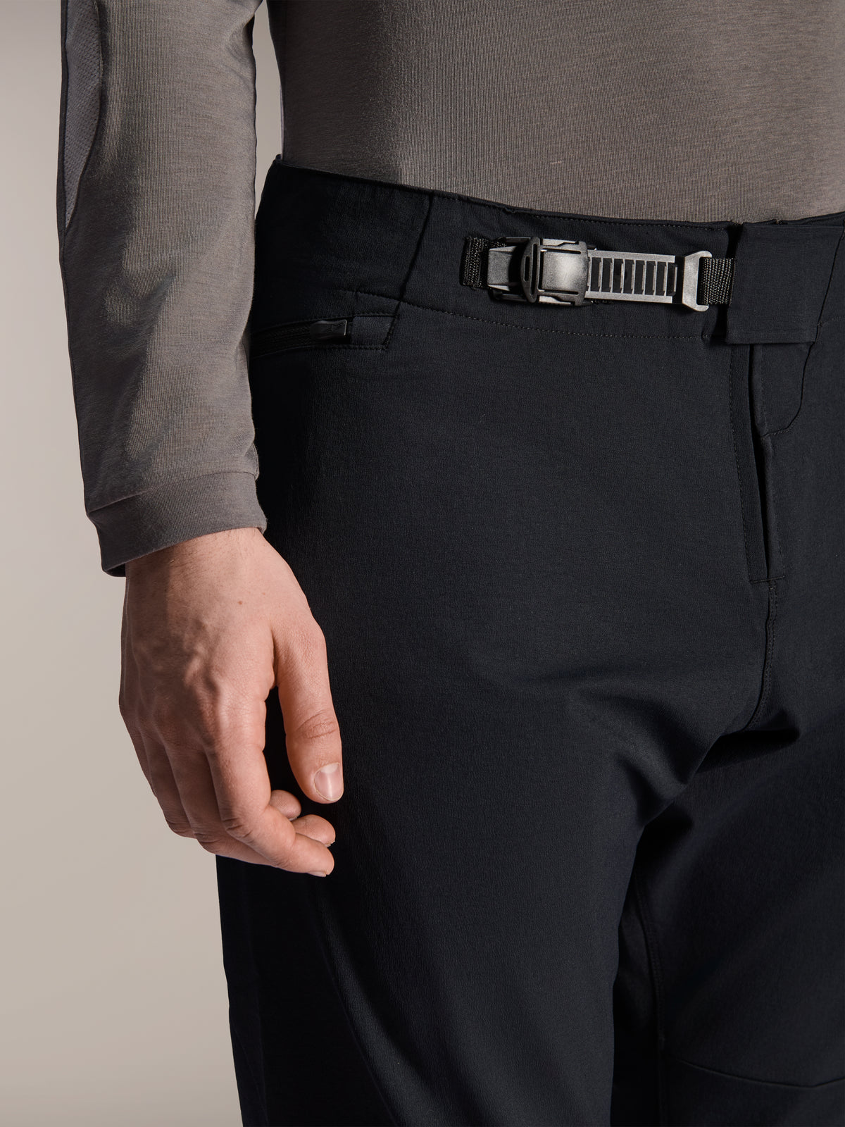 Alpinestars A-Dura Elite broek, zwart, close-up van de ratelsluiting en ritssluiting aan de voorkant, zijzak met rits, technische mountainbikebroek van duurzame Cordura-stof