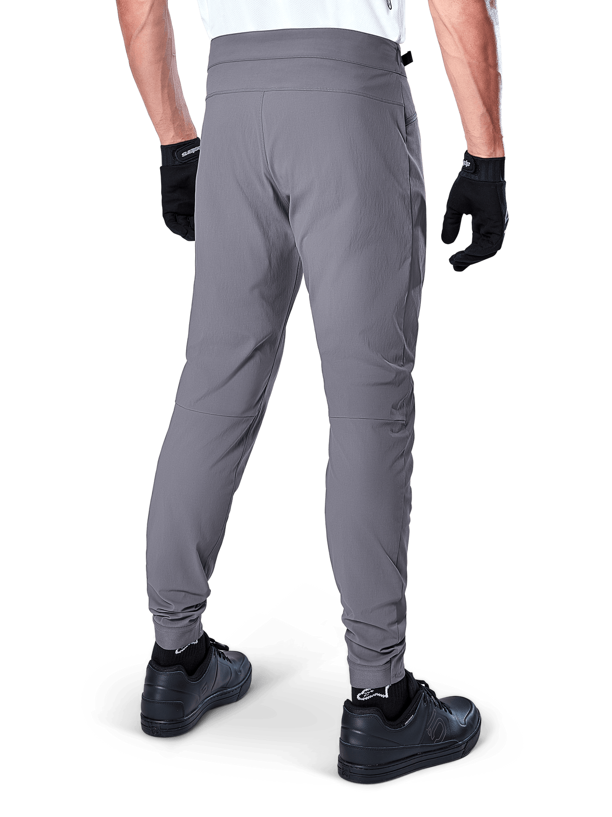 Alpinestars A-Dura Pants, mountainbikebroek, donkergrijs, achteraanzicht van model die de kleding draagt, voorzien van een duurzame 2-way stretchstof en elastische boorden, gecombineerd met zwarte handschoenen en sneakers voor een complete fietslook