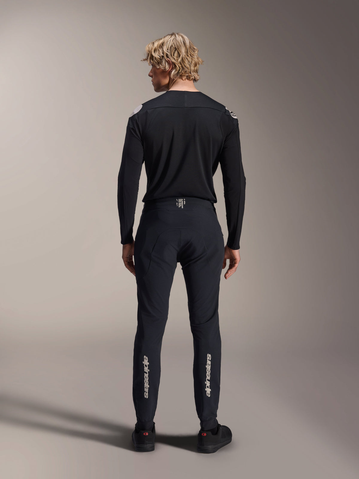 Alpinestars A-Aria Polartec Elite Long Sleeve Jersey, Black MTB Jersey, rear view worn with matching black pants, performance fit for mountain biking, featuring technical moisture-wicking fabric and subtle branding on the lower back