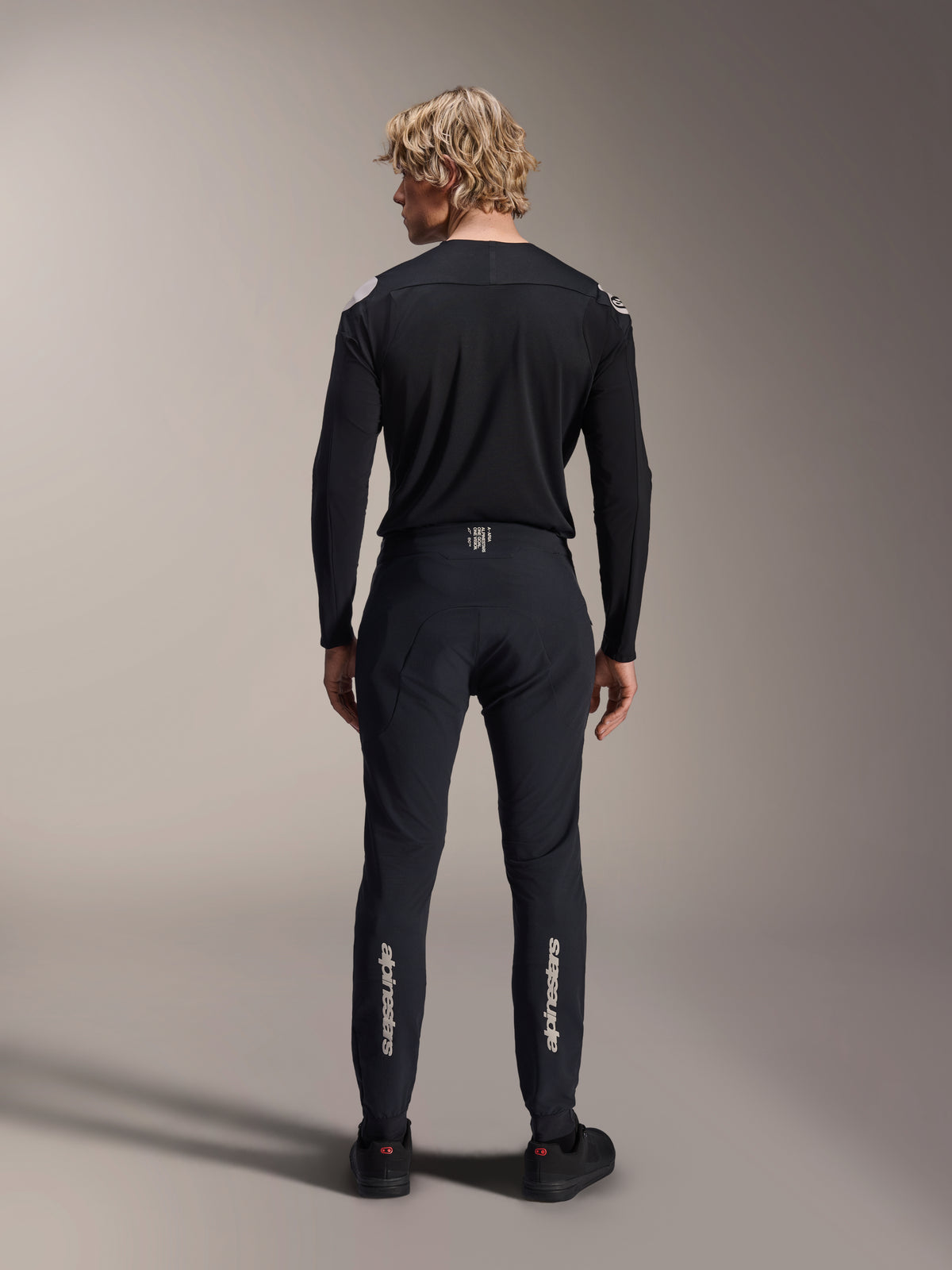 Alpinestars A-Aria Elite Pants, Black Titanium, back view on male model, featuring silver Alpinestars branding on the lower legs, technical MTB pants with a performance fit and moisture-wicking waistband detail.