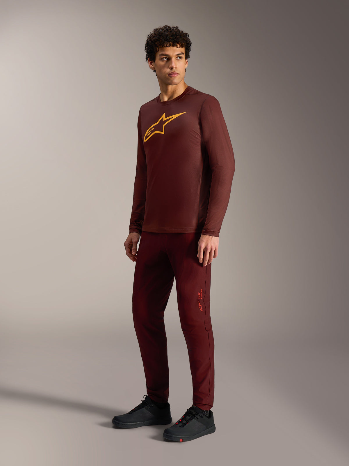 Bordeaux A-Dura Ride Long Sleeve Jersey with yellow Astars logo, styled with matching pants and black cycling shoes.
