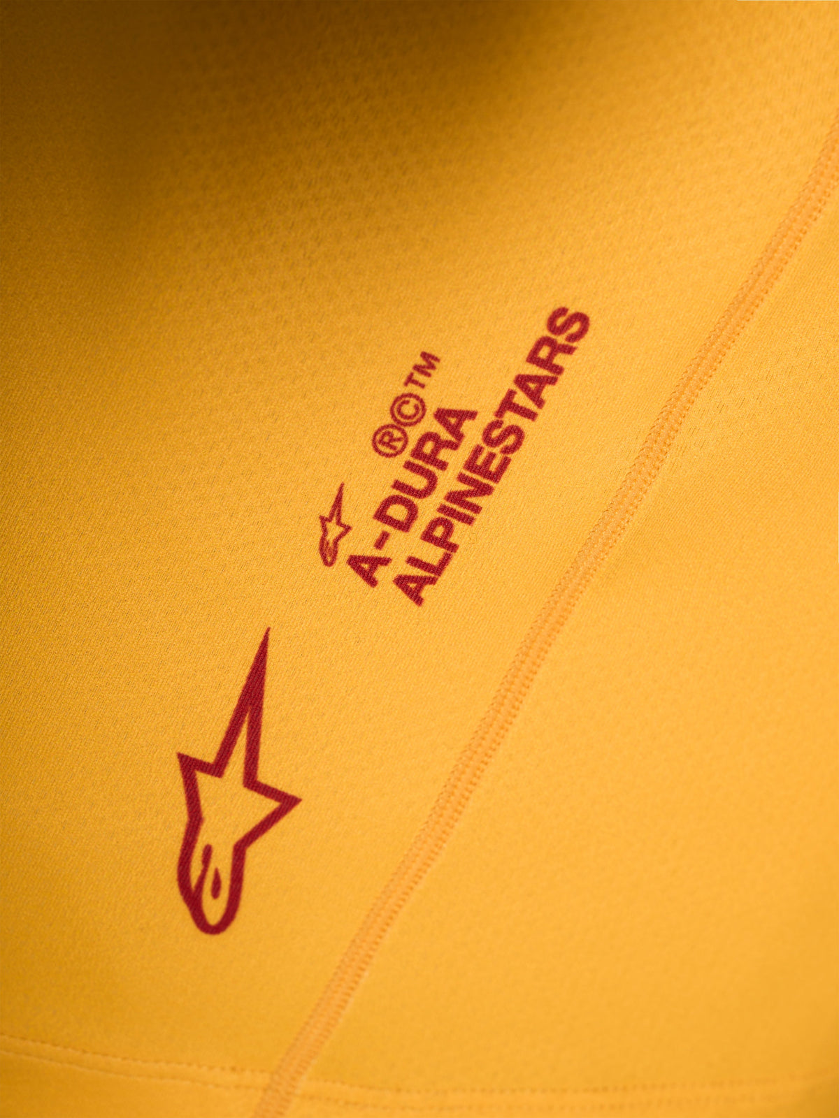 Detail van de oranje A-Dura Ride jersey met rood Alpinestars logo en woordmerk op rekbare stretchstof.