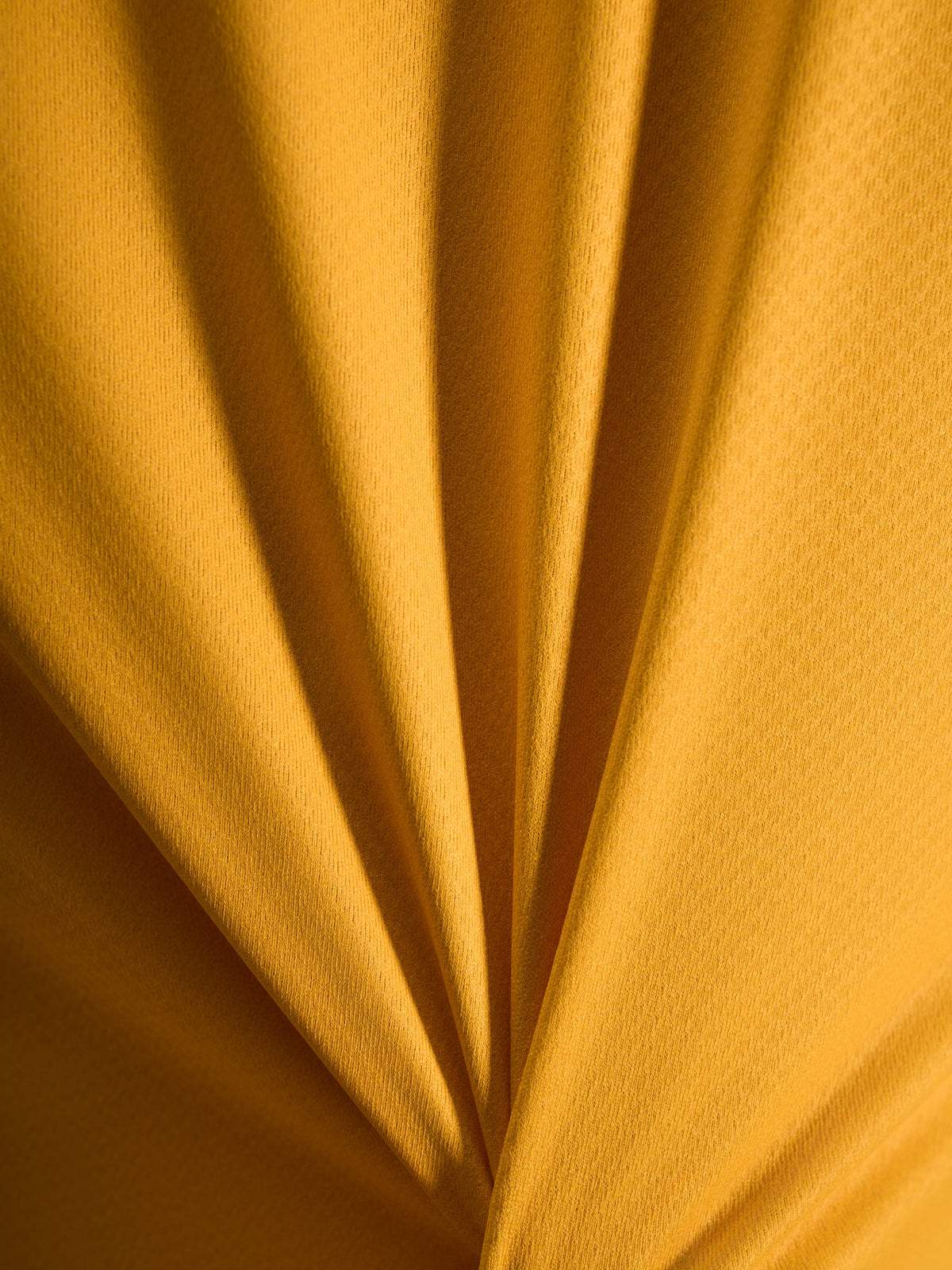 Close-up van de oranje A-Dura Ride Jersey textuur, lichtgewicht jacquard poly/spandex materiaal.