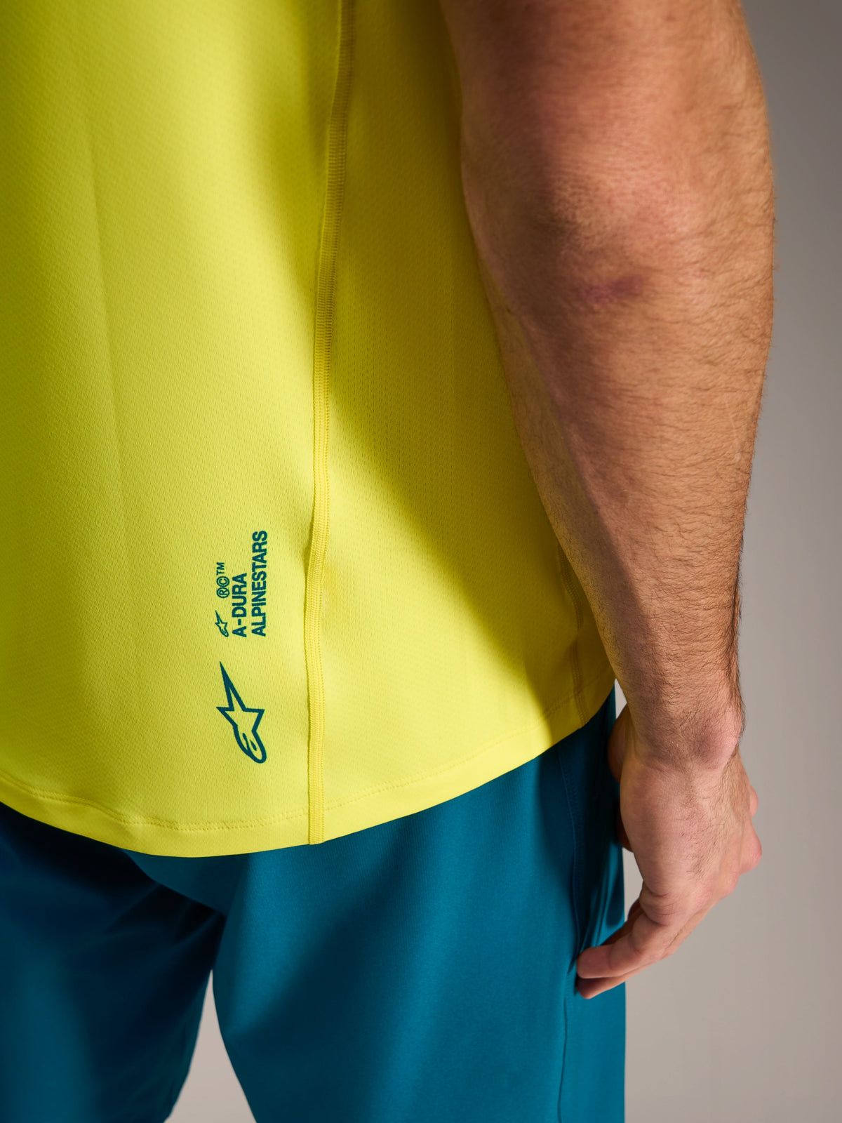 Geel fluo A-Dura Ride fietsshirt, detail van Alpinestars-logo op de onderrug, lichtgewicht MTB-kleding.