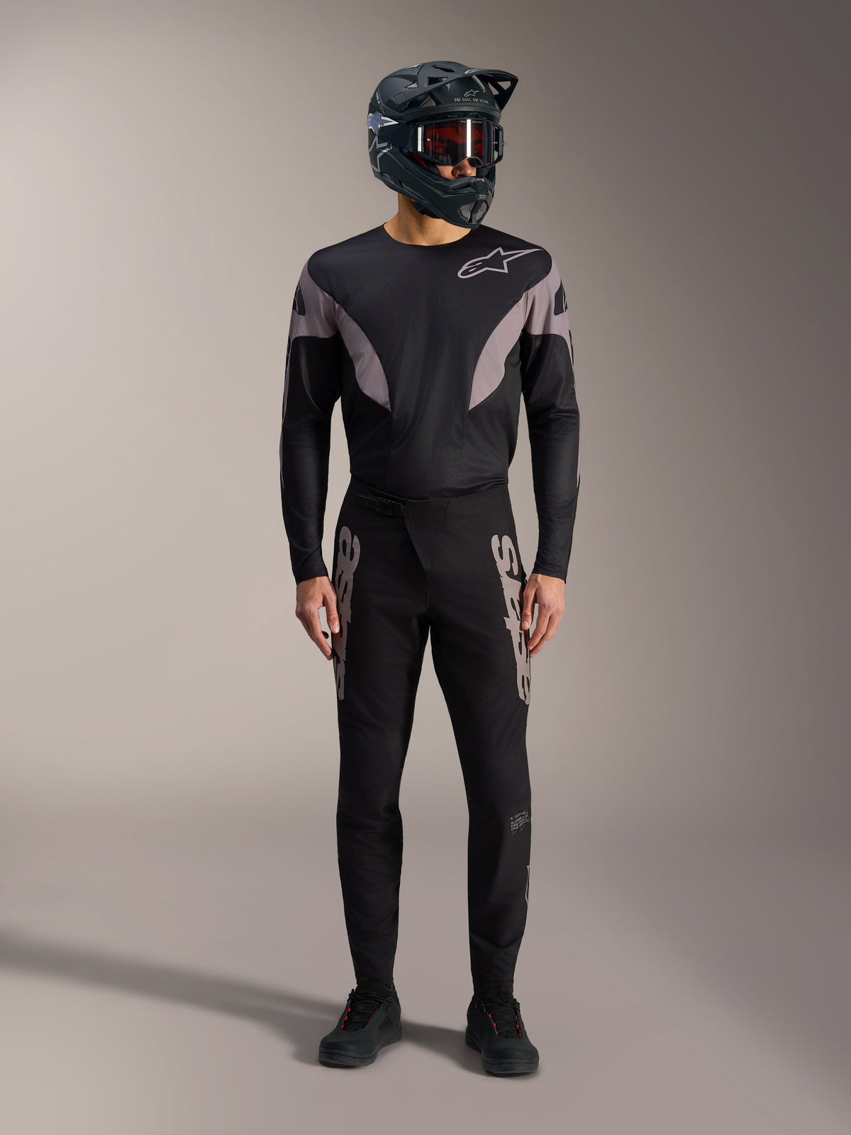 Zwarte A-Supra Elite MTB-kit met jersey met lange mouwen, racebroek met grijze logo's en integraalhelm.