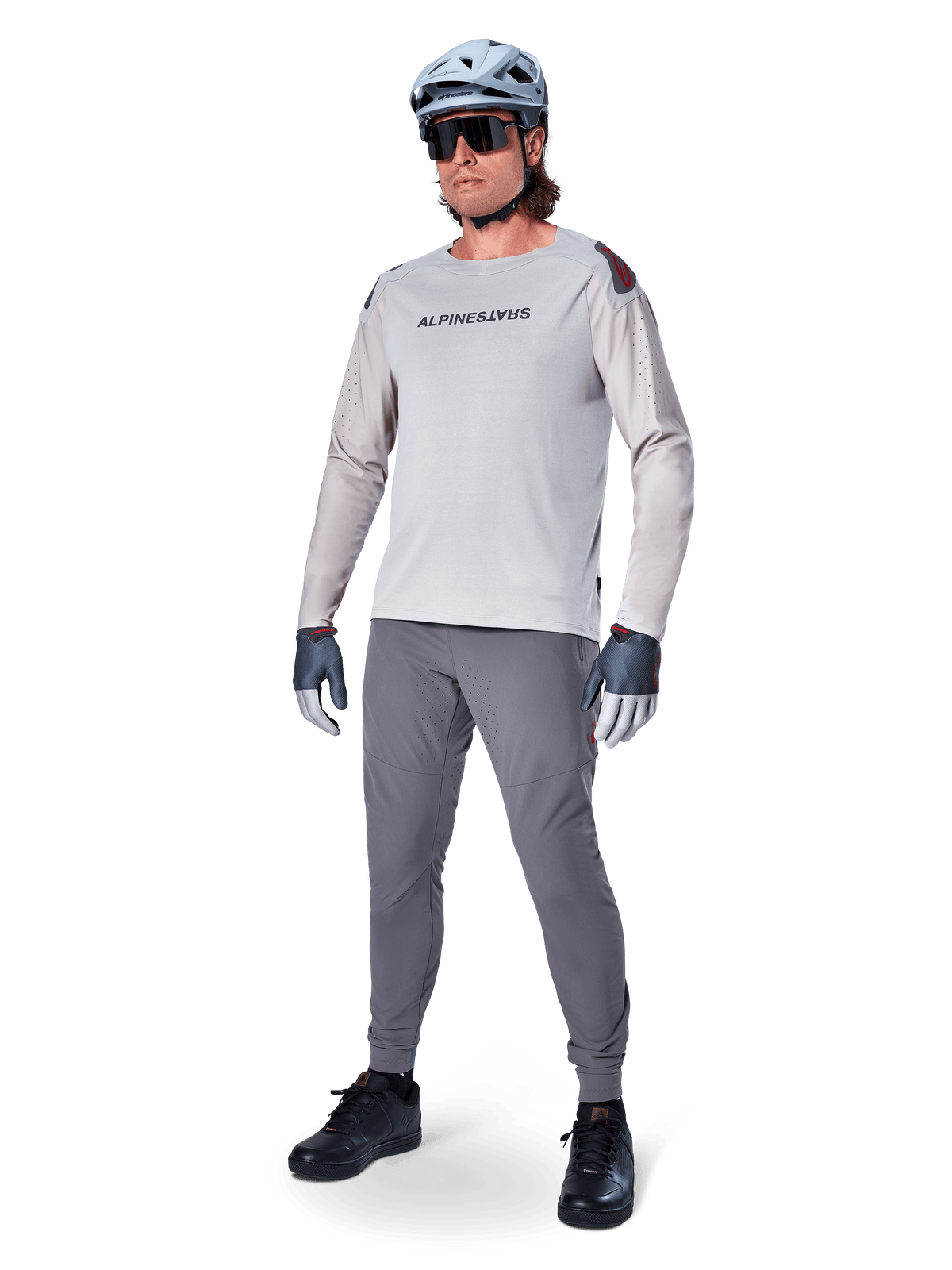 Alpinestars A-Aria Polartec Switch Jersey, Long Sleeve MTB Jersey, Light Gray, worn with dark gray mountain bike pants, helmet, and gloves, featuring laser-perforated sleeves and Alpinestars branding on the chest.