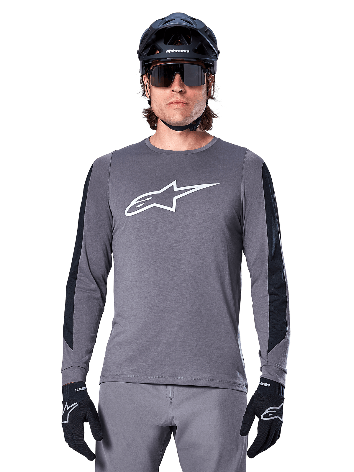 Alpinestars A-Dura Dri Astar Long Sleeve Jersey, Dark Gray, featuring a large white Astar logo on the chest and black mesh arm panels, worn by a rider with a black mountain bike helmet and performance sunglasses, MTB cycling apparel