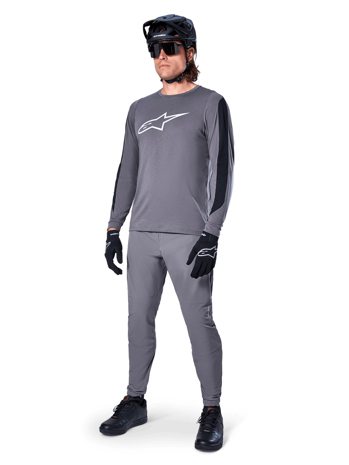 Alpinestars A-Dura Dri Astar Jersey, Long Sleeve MTB Jersey, Dark Gray with white chest logo, black mesh panels on sleeves, worn with matching gray pants, black helmet, and gloves, performance mountain bike apparel