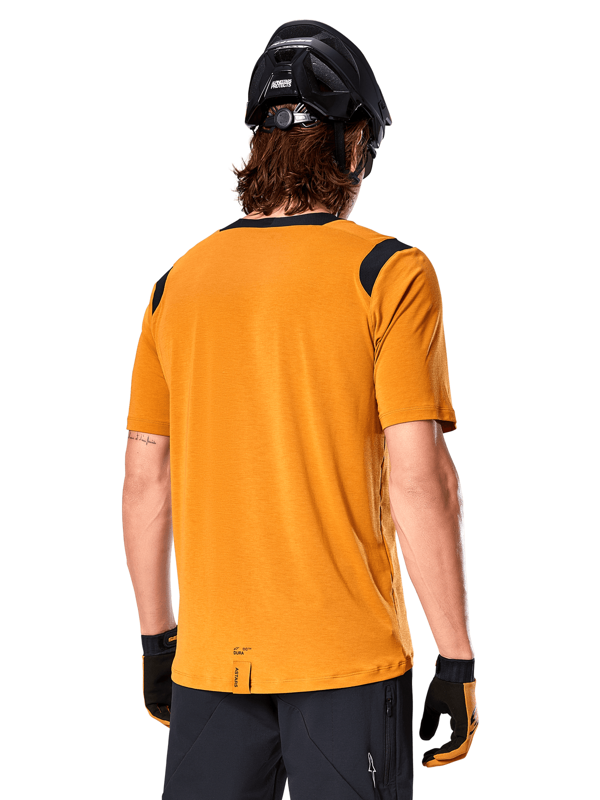 Alpinestars A-Dura Dri Wool Jersey met korte mouwen, donkergoud, achteraanzicht van een man die de jersey draagt met zwarte mesh panelen op de schouders, gecombineerd met een zwarte MTB-helm en handschoenen, mountainbike-uitrusting met normale pasvorm.