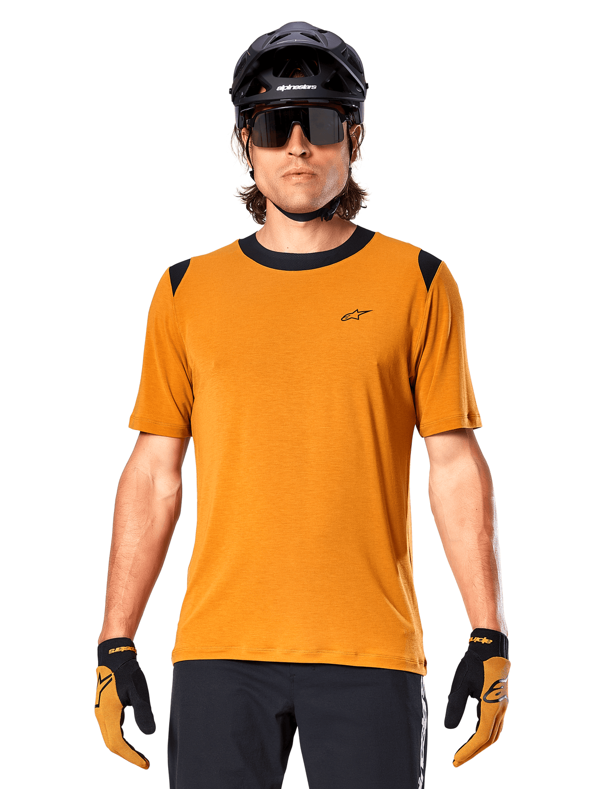 Alpinestars A-Dura Dri Wool Jersey met korte mouwen, Dark Gold, gedragen met zwarte MTB-helm, zonnebril en handschoenen, voorzien van zwarte kraag- en schouderpanelen, ademende drirelease® wolmix voor mountainbiken