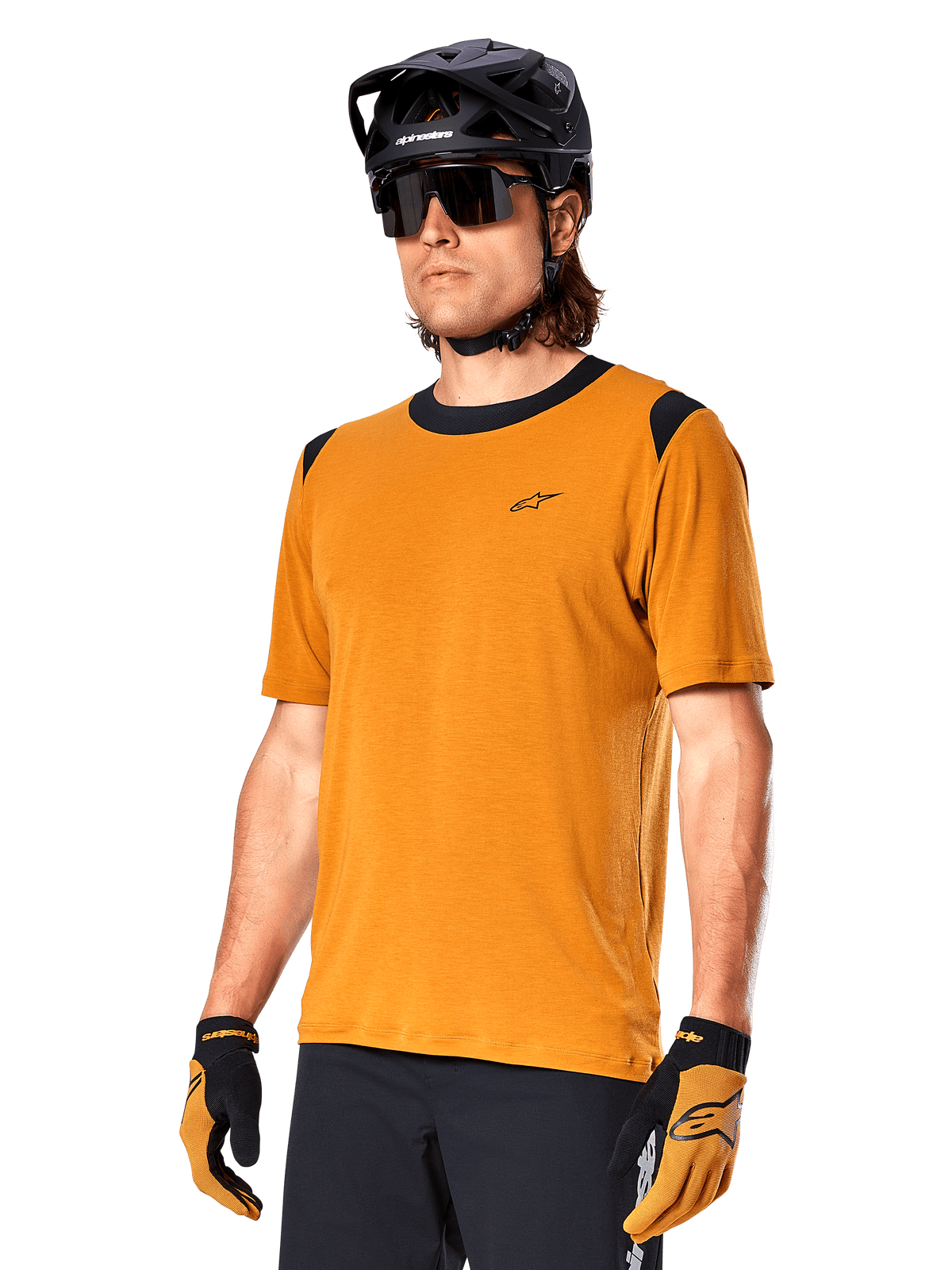 Alpinestars A-Dura Dri Wool Jersey met korte mouwen, MTB-fietsshirt, donkergoud met zwarte accenten, technisch shirt van wolmix met korte mouwen en zwarte schouderpanelen, gedragen met zwarte mountainbikehelm en bijpassende handschoenen