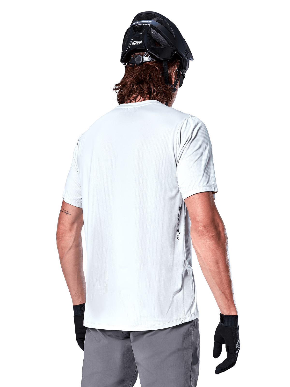 Alpinestars A-Dura Oscar Jersey, Short Sleeve MTB Jersey, White Dove, back view on a rider wearing a black cycling helmet, grey shorts, and black gloves, technical performance cycling gear