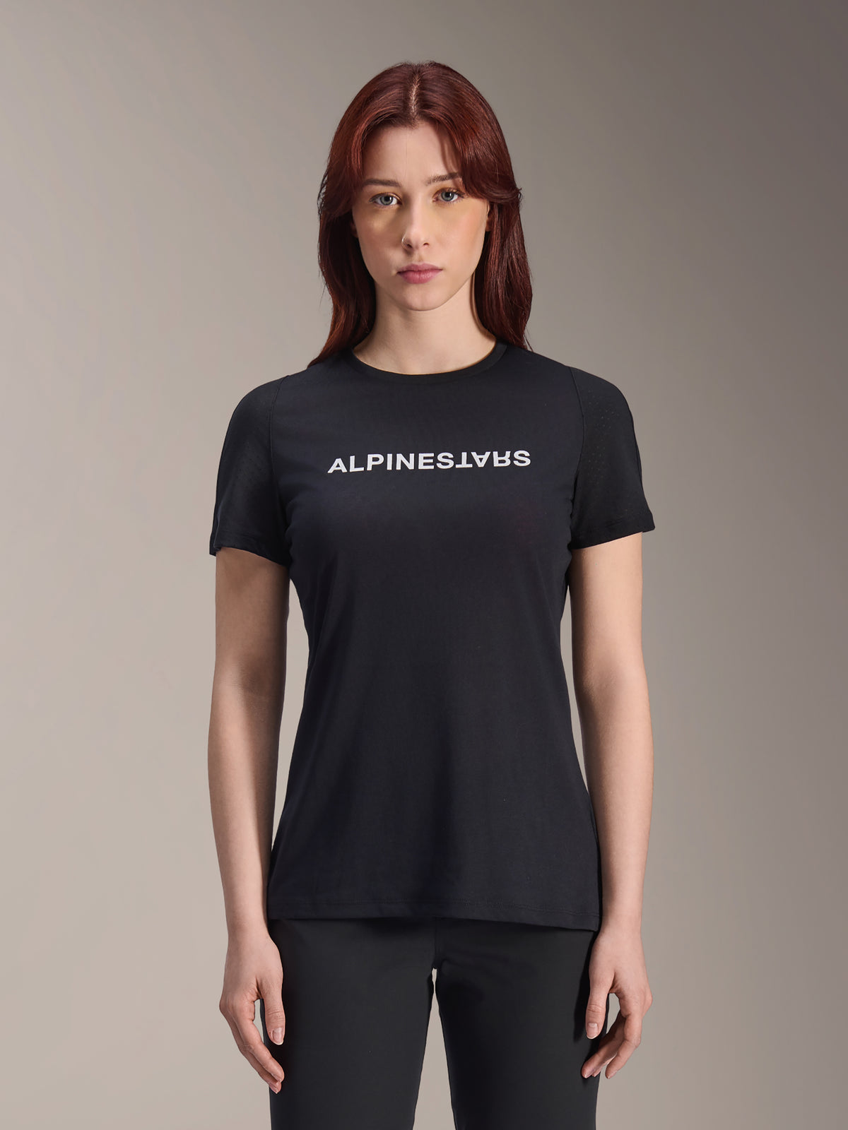 Alpinestars Stella A-Dura Dri Switch Jersey, MTB-shirt met korte mouwen voor dames, zwart met wit Alpinestars-logo op de borst, casual performance pasvorm, technische vochtafvoerende stof voor mountainbiken, vrouw met rood haar draagt het shirt