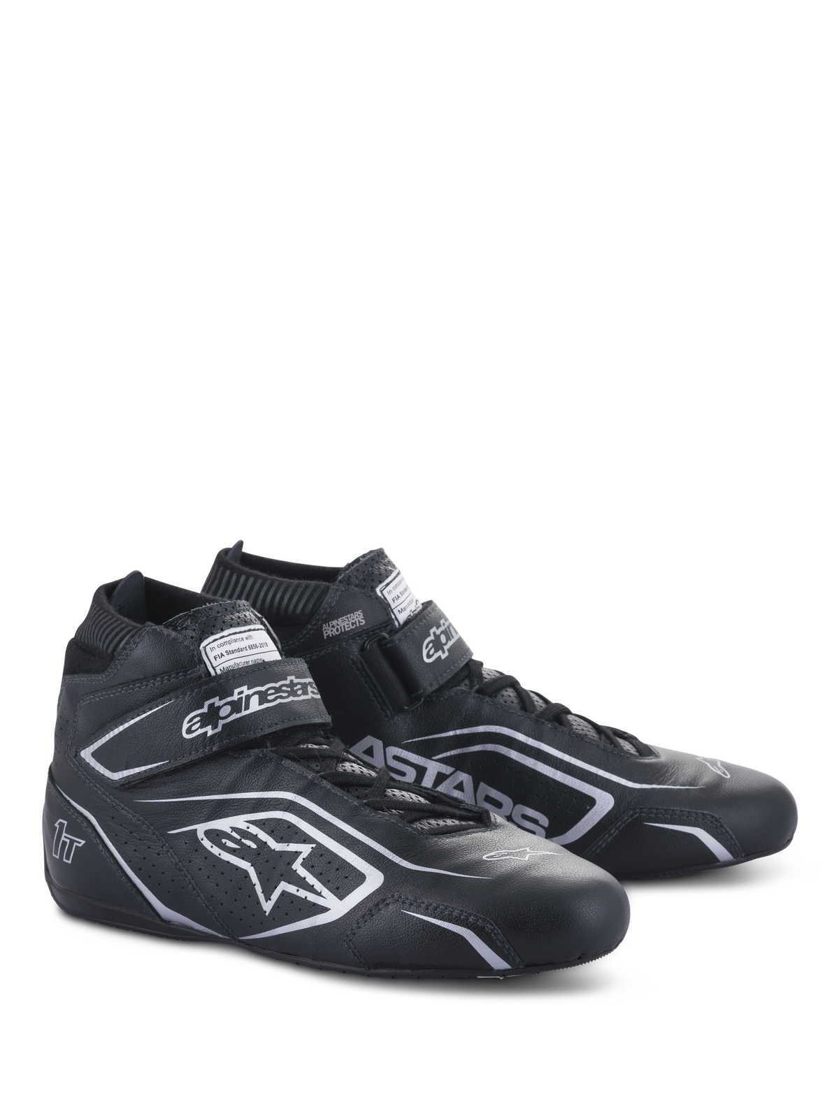 Alpinestars Tech-1 T V3 FIA-schoenen, autoraceschoenen, zwart en zilver, constructie van runderleer met zilveren Alpinestars-logo's en branding, schuin zijaanzicht met klittenbandsluiting en vetersluiting
