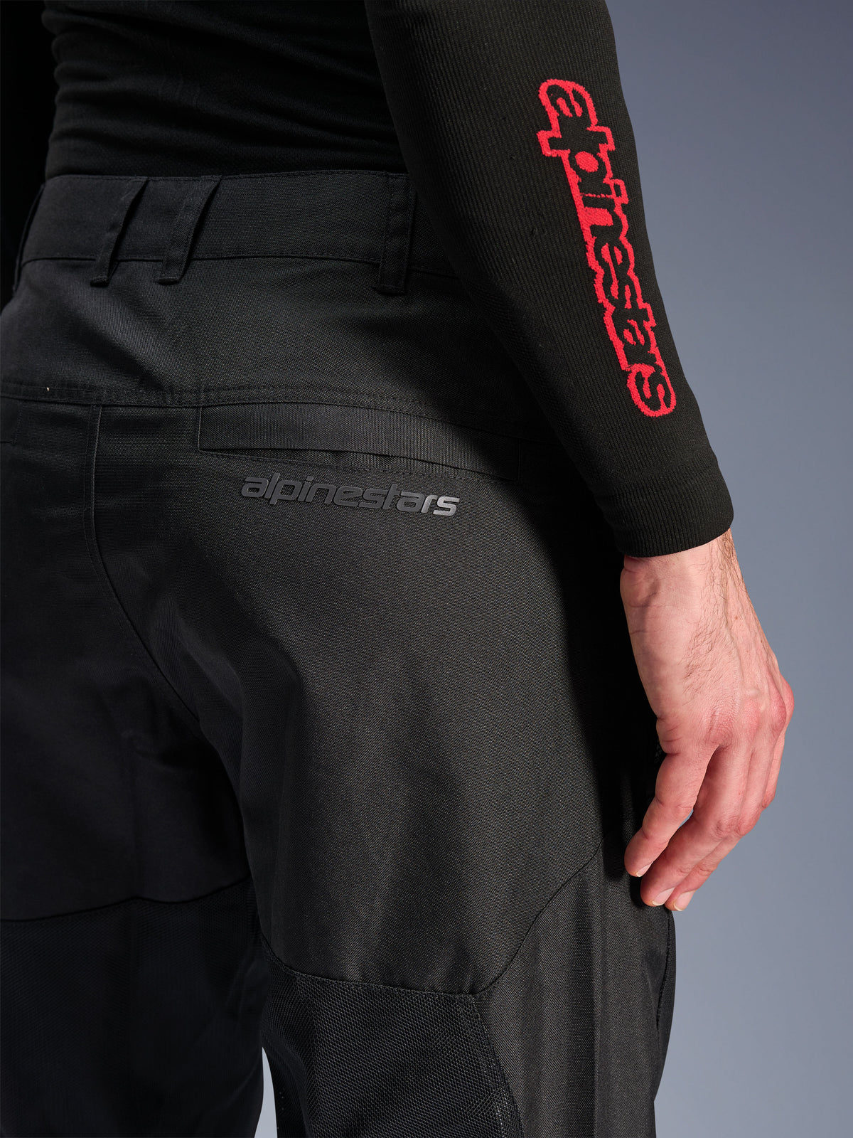Alpinestars C-1 Air Broek, zwarte textiele motorbroek, close-up van de achterzak met een subtiel grijs Alpinestars-logo, voorzien van ademende mesh-panelen en duurzame polystof, ontworpen voor stedelijk rijcomfort