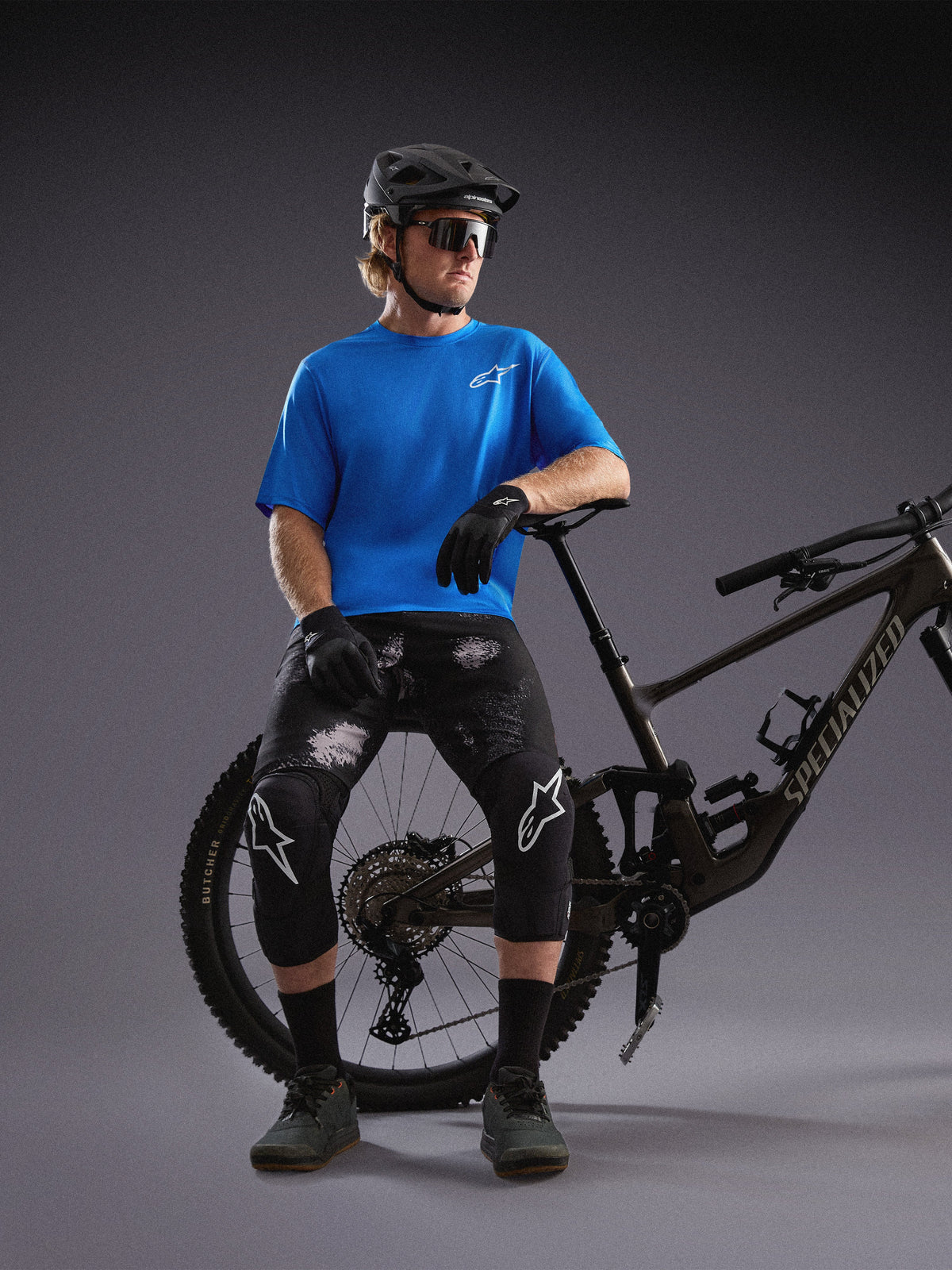 Blauwe Alpinestars A-Dura Air SS Jersey en Black Camo Ride Shorts gedragen door mountainbiker in studio.