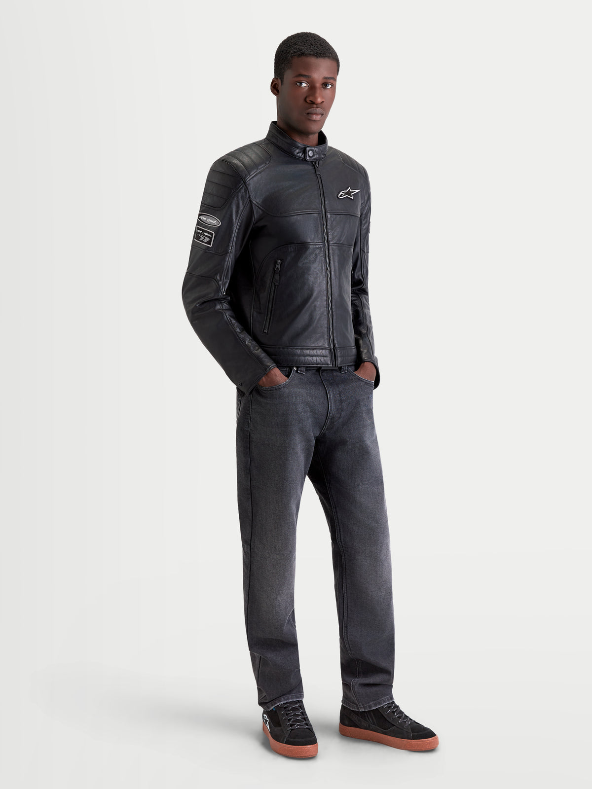 Alpinestars Revern Leren jas, urban heren motorjas in zwart, vooraanzicht op een model met donkere jeans en motorschoenen, met heritage styling en constructie van verweerd volnerfleer