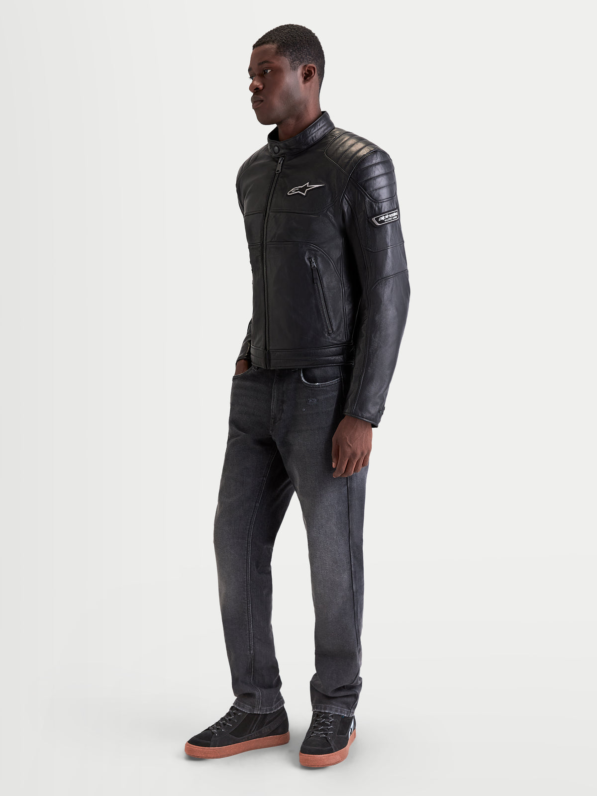 Alpinestars Revern leren jas, urban motorjas voor heren in het zwart, zijaanzicht gedragen door een model met heritage-stijl en volnerfleer constructie