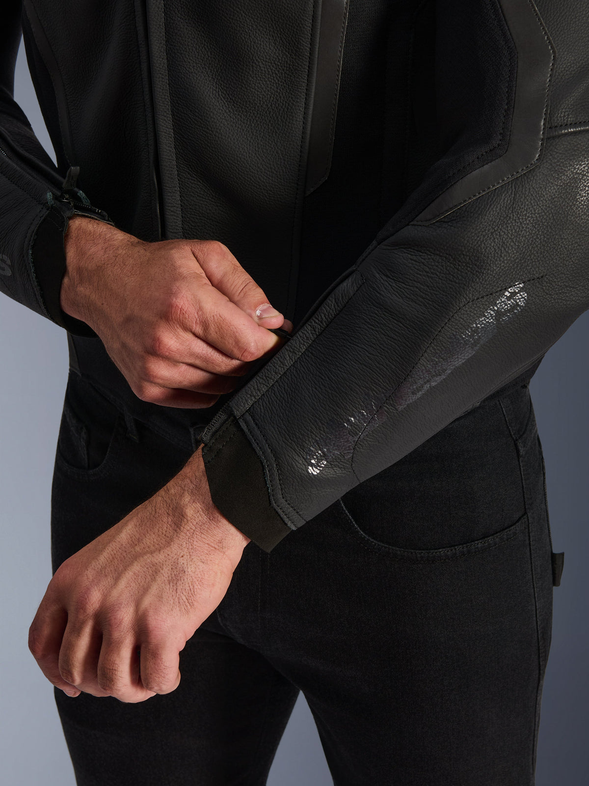 Alpinestars GP Force V2 Leren Jas, zwart, close-up van het ergonomische mouwmanchet, persoon verstelt de polssluiting, hoogwaardige constructie van runderleer met technische details voor sportief motorrijden