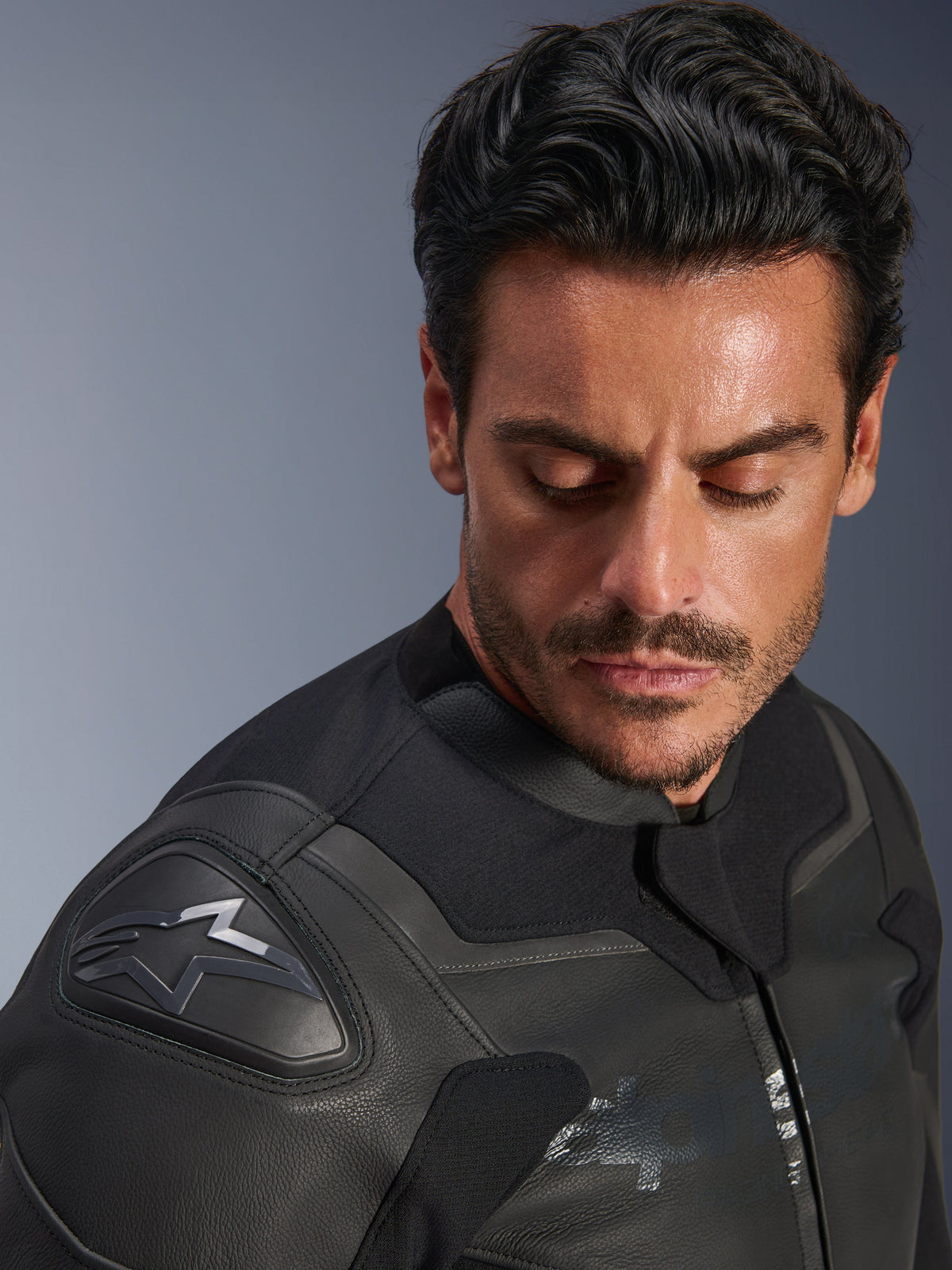 Alpinestars GP Force V2 leren jas, zwart, close-up van een mannelijk model dat de jas draagt, gericht op de schouder met de GP Lite Evo DFS-beschermer en het Alpinestars-logo, premium meerpanelige leren constructie
