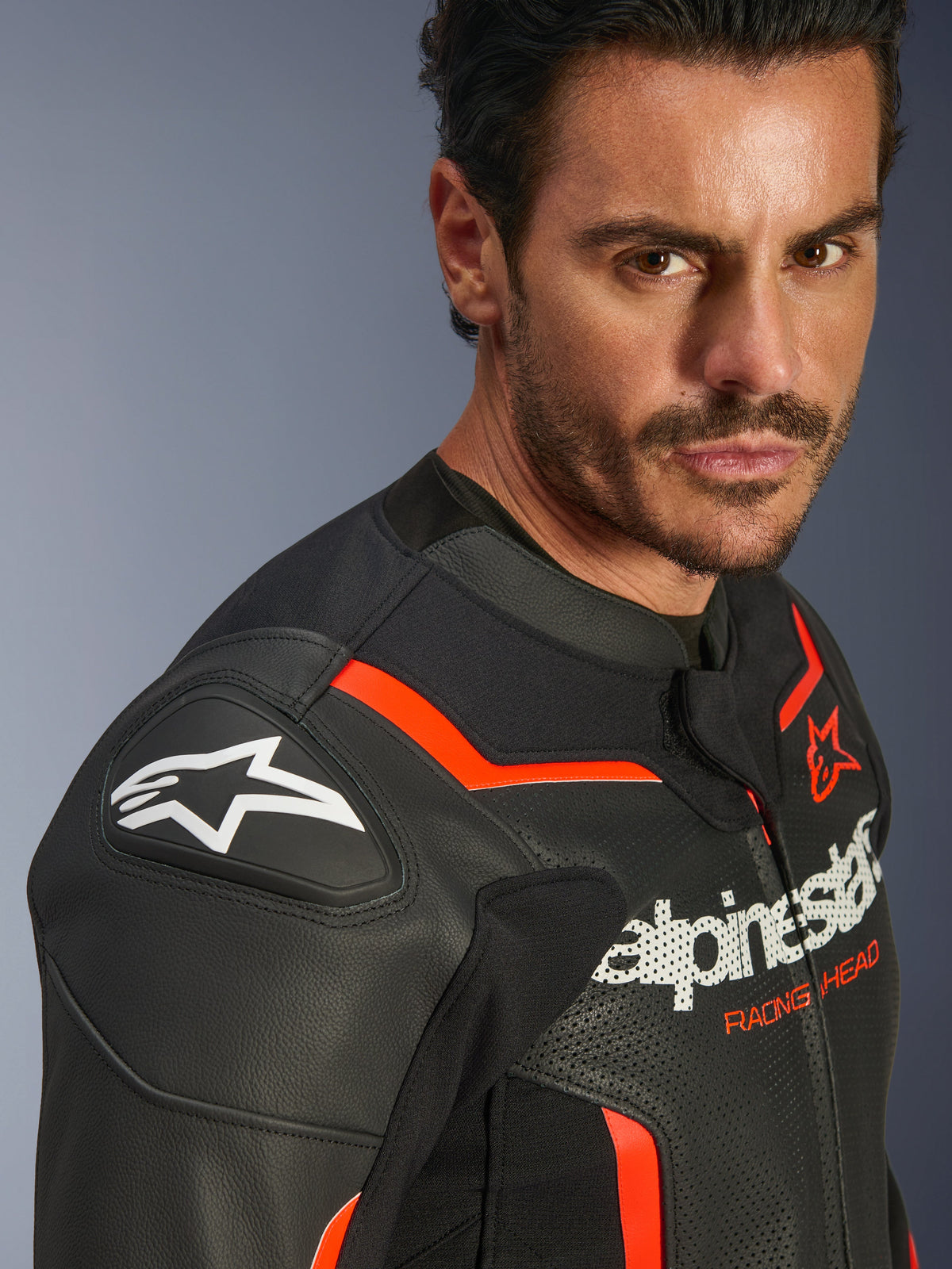 Alpinestars GP Force V2 Airflow Leather Jacket, Black Red Fluo, worn by a male model, featuring perforated leather, GP Lite Evo DFS shoulder sliders, and Alpinestars logo branding, sport motorcycle protective gear