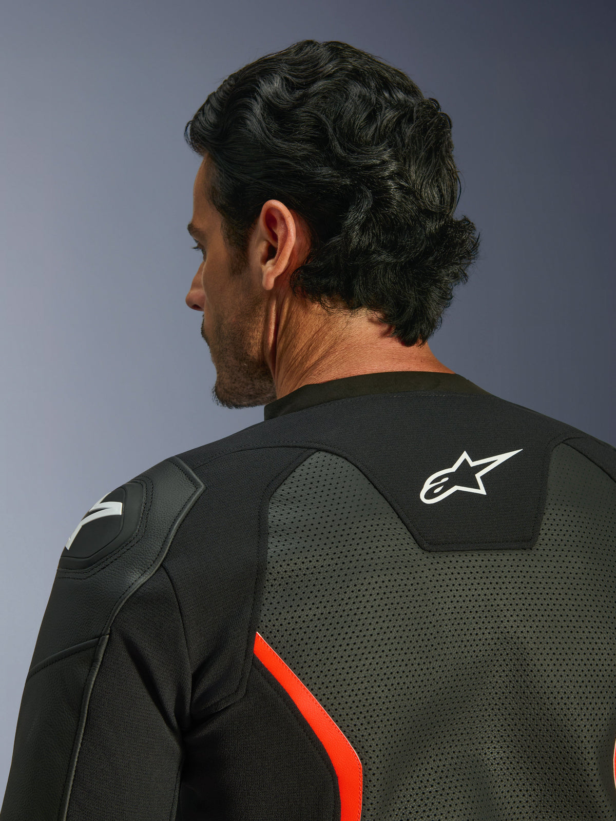 Alpinestars GP Force V2 Air Leather Jacket, Black and Red Fluo, close-up of the upper back and shoulder, featuring extensive leather perforations for airflow, white logo on the back, and GP Lite Evo shoulder protection