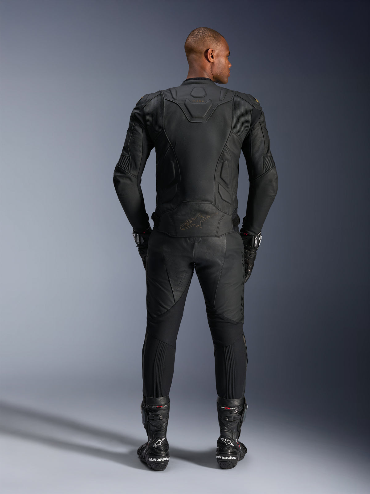 Alpinestars Dusk leren jas, zwarte runderlederen motorracejas, achteraanzicht van een rijder in beschermende uitrusting.