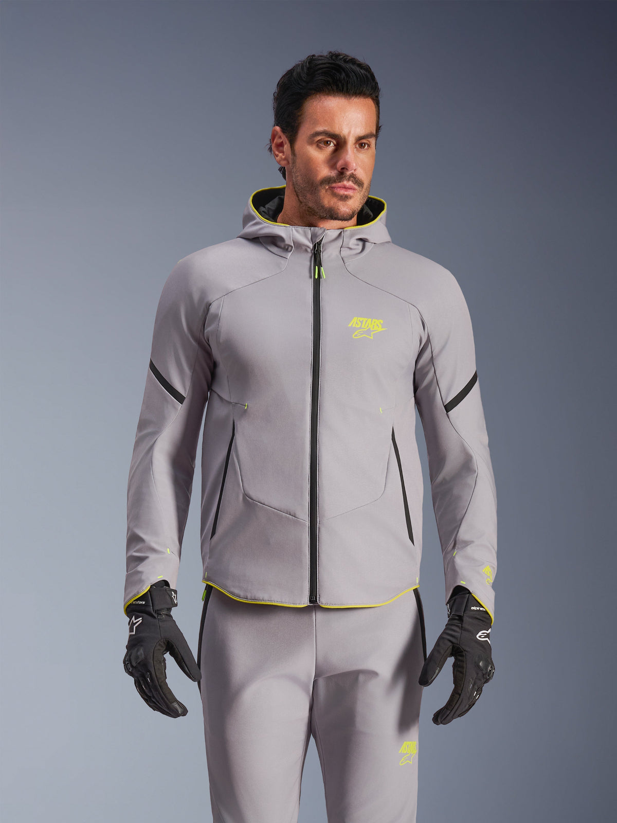 Alpinestars Aeroshell Waterproof Jacket, Mid Gray and Yellow Fluo, hooded motorcycle softshell jacket with black zippers, worn with matching gray pants and black gloves, waterproof performance gear for road riding