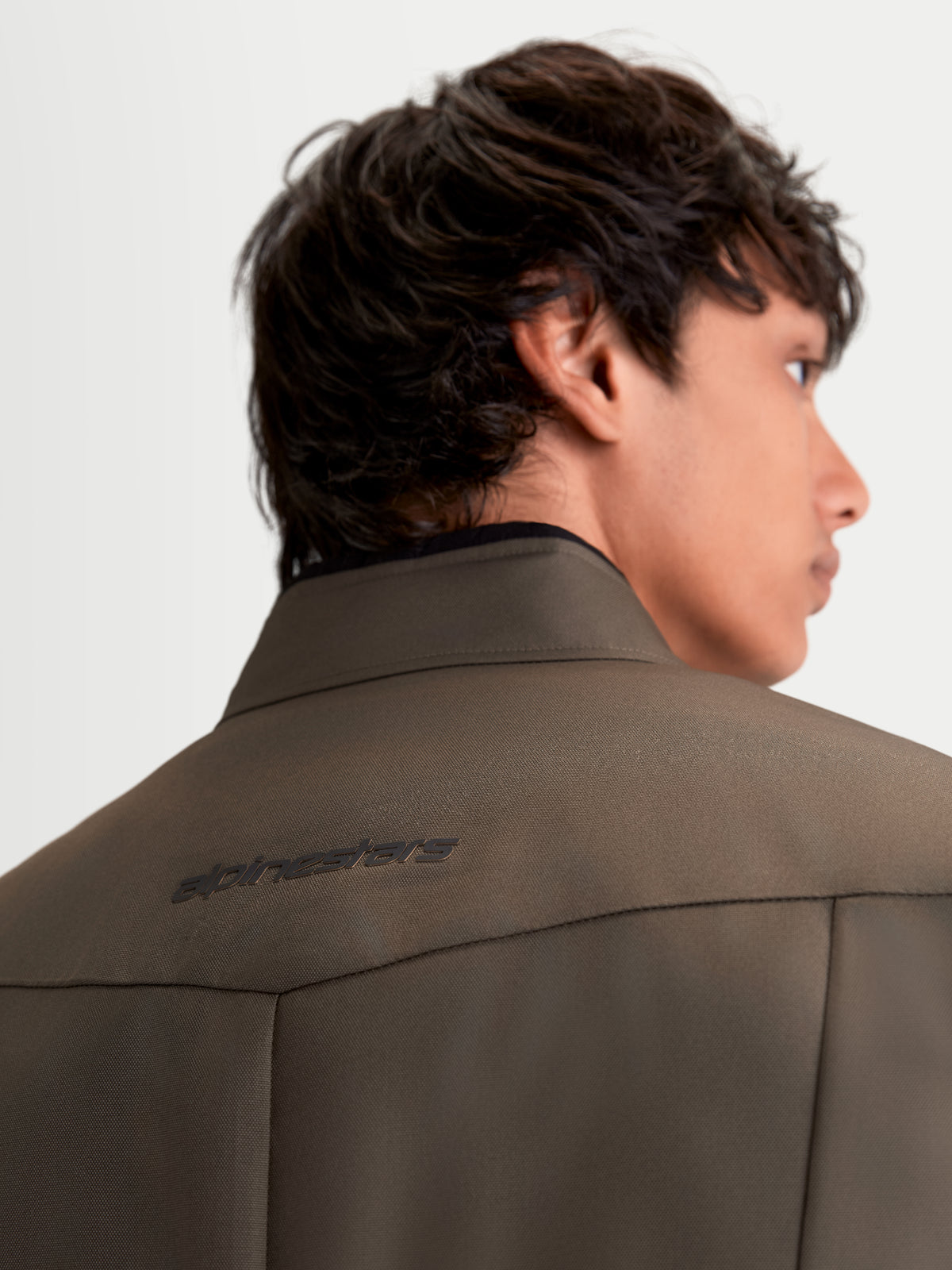 Alpinestars C-1 Waterproof jas, urban contemporary motorjas van textiel in walnootkleur en zwart, detailopname van de achterkant met 3D-rugpatroon en kraag gedragen door een model