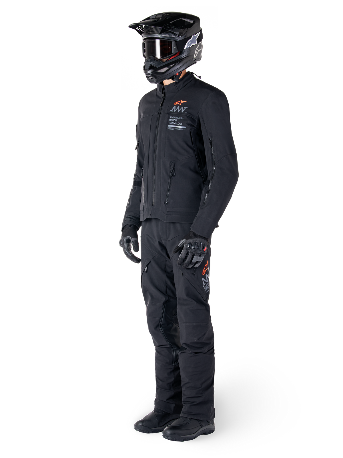 Alpinestars AMT-8 Stretch Drystar® XF jas, adventure motorjas, zwart, gedragen met bijpassende broek, helm en handschoenen, voorzien van Alpinestars Motion Technology branding met oranje accenten, duurzame stretchconstructie voor adventure rijden