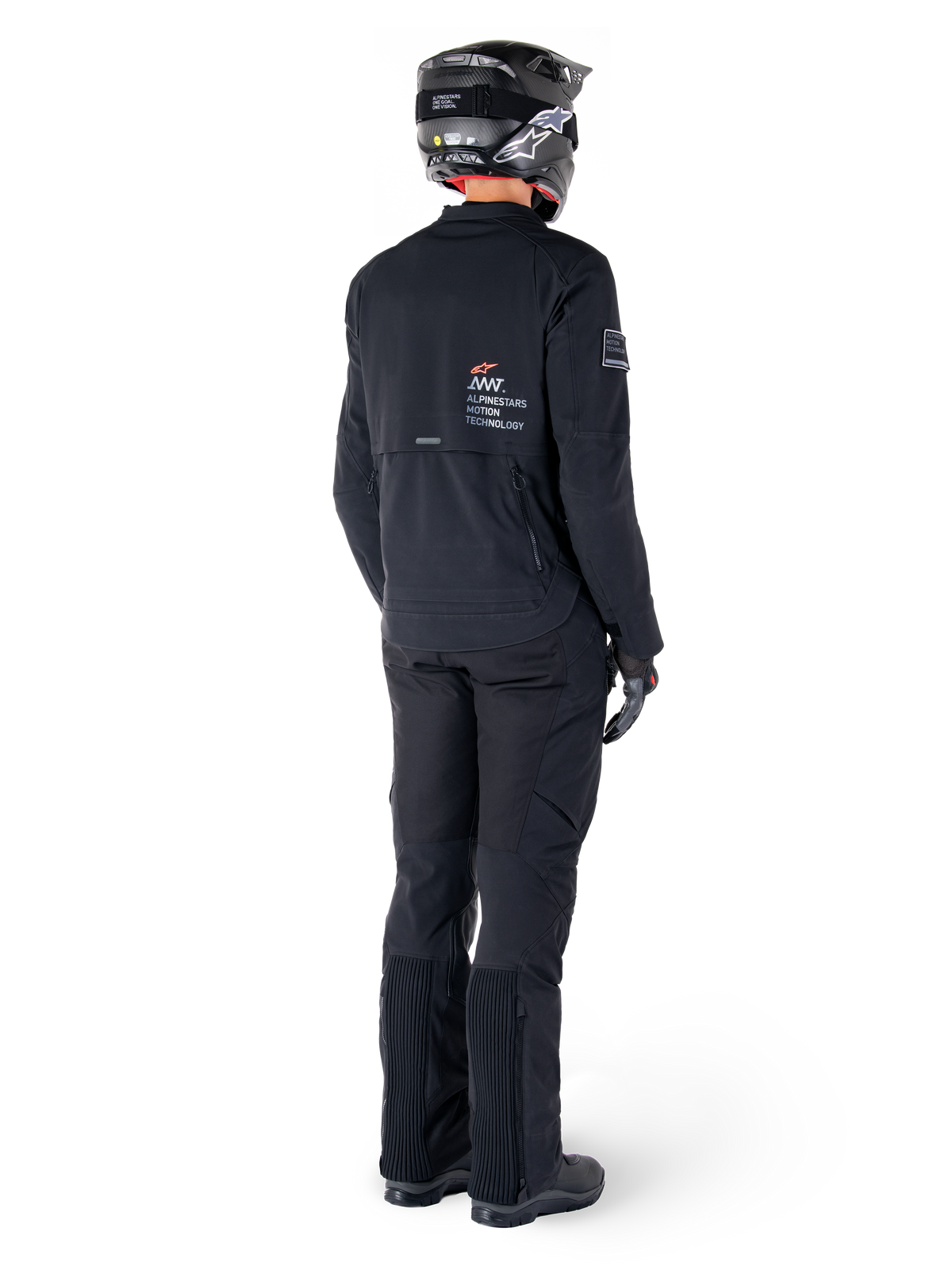Alpinestars AMT-8 Stretch Drystar® XF Jas, zwart, achteraanzicht van een motorrijder die de jas draagt met bijpassende zwarte broek en een zwarte helm, voorzien van 'Alpinestars Motion Technology' branding op de rug, technisch stretchmateriaal voor adventure motorrijden