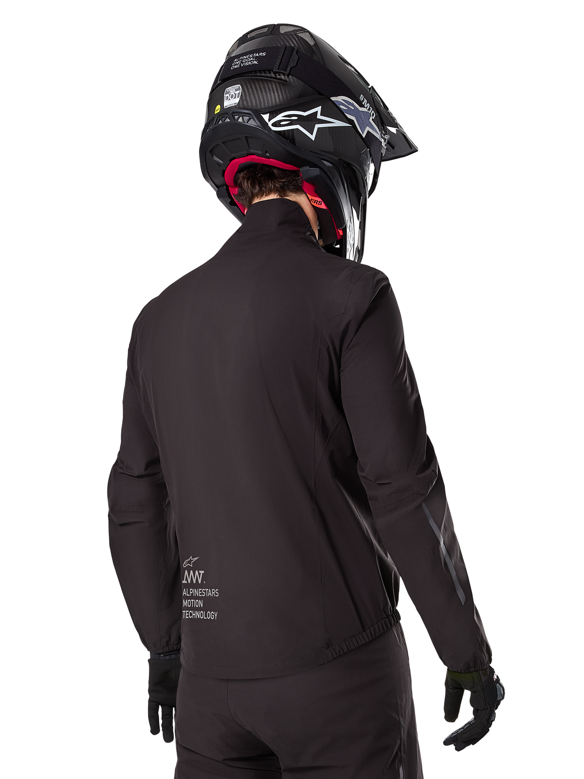 Alpinestars AMT-8 Stretch Drystar® XF voering, zwarte waterdichte voering voor motorjas, achteraanzicht van een rijder met zwarte helm en handschoenen, voorzien van Alpinestars Motion Technology-branding op de onderrug, minimalistisch en functioneel ontwerp voor adventure ritten.