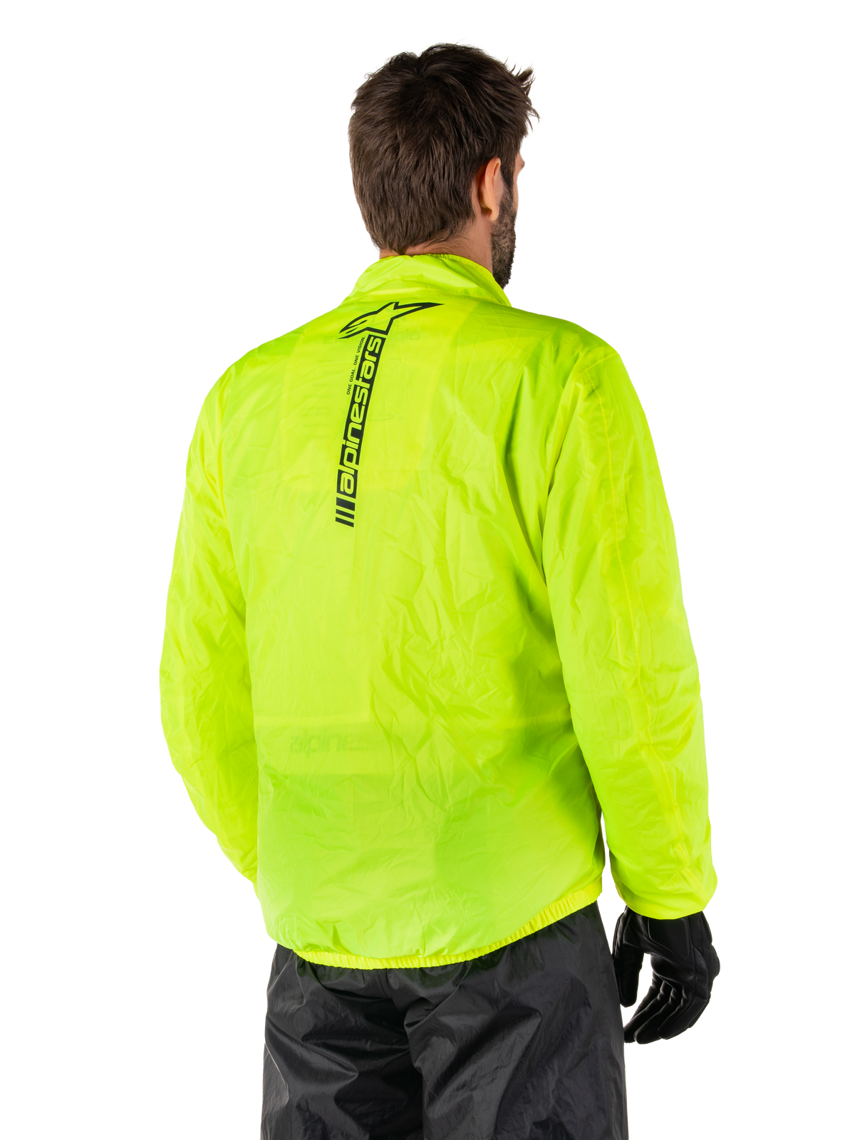 Alpinestars Hurricane Rain V2 Jas, Yellow Fluo, achteraanzicht gedragen door mannelijk model, met verticaal zwart Alpinestars-woordmerk op het midden van de rug, elastische taille en manchetten, waterdicht en opvouwbaar ontwerp