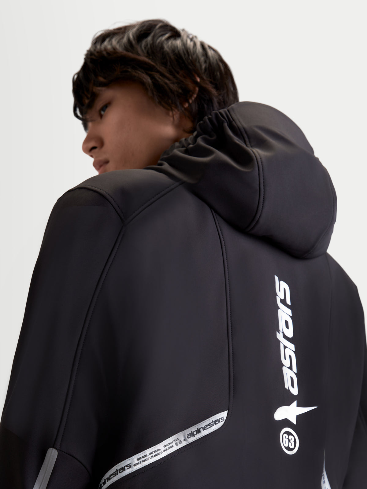 Alpinestars C 5 Drystar jas, heren urban contemporary textiel motorjas, zwart, achteraanzicht met geïntegreerde capuchon en reflecterende brandinggedetails gedragen door een model