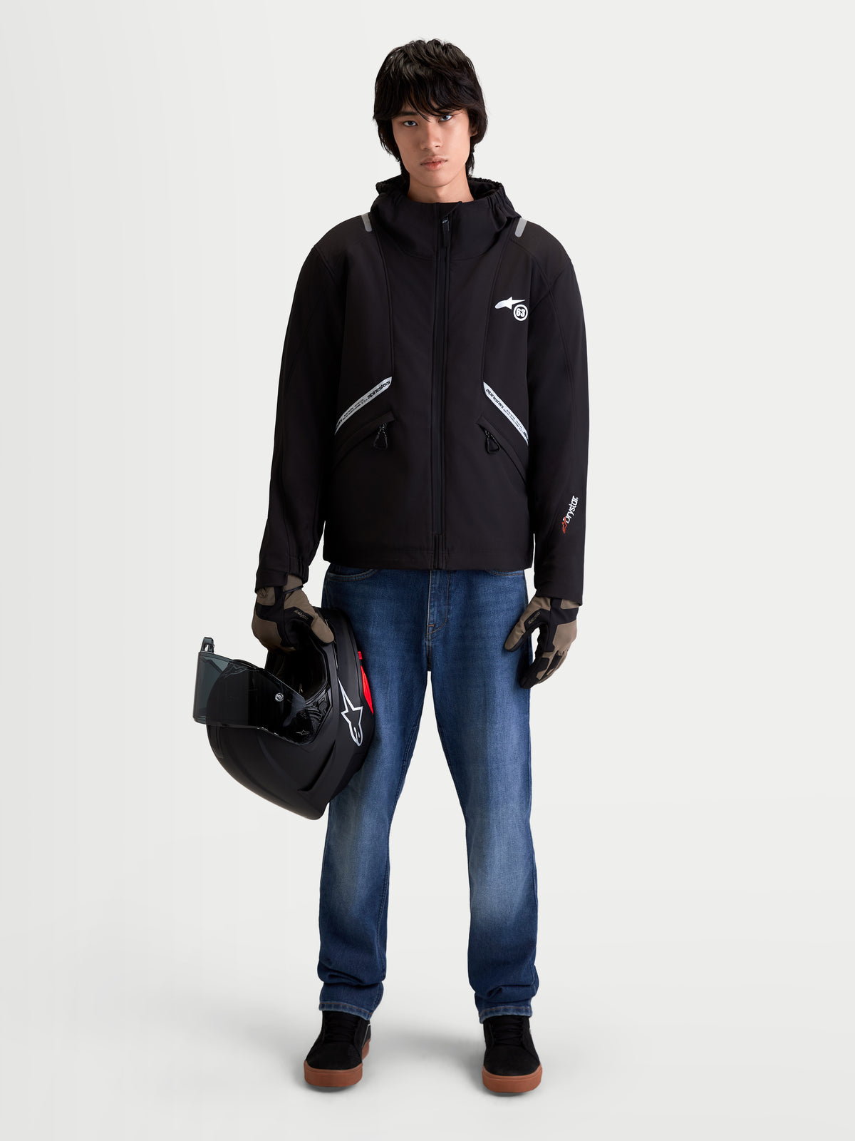 Alpinestars C 5 Drystar jas, heren urban contemporary motorjas, zwart, vooraanzicht op model met spijkerbroek, handschoenen en helm, met waterdichte softshell constructie en geïntegreerde capuchon