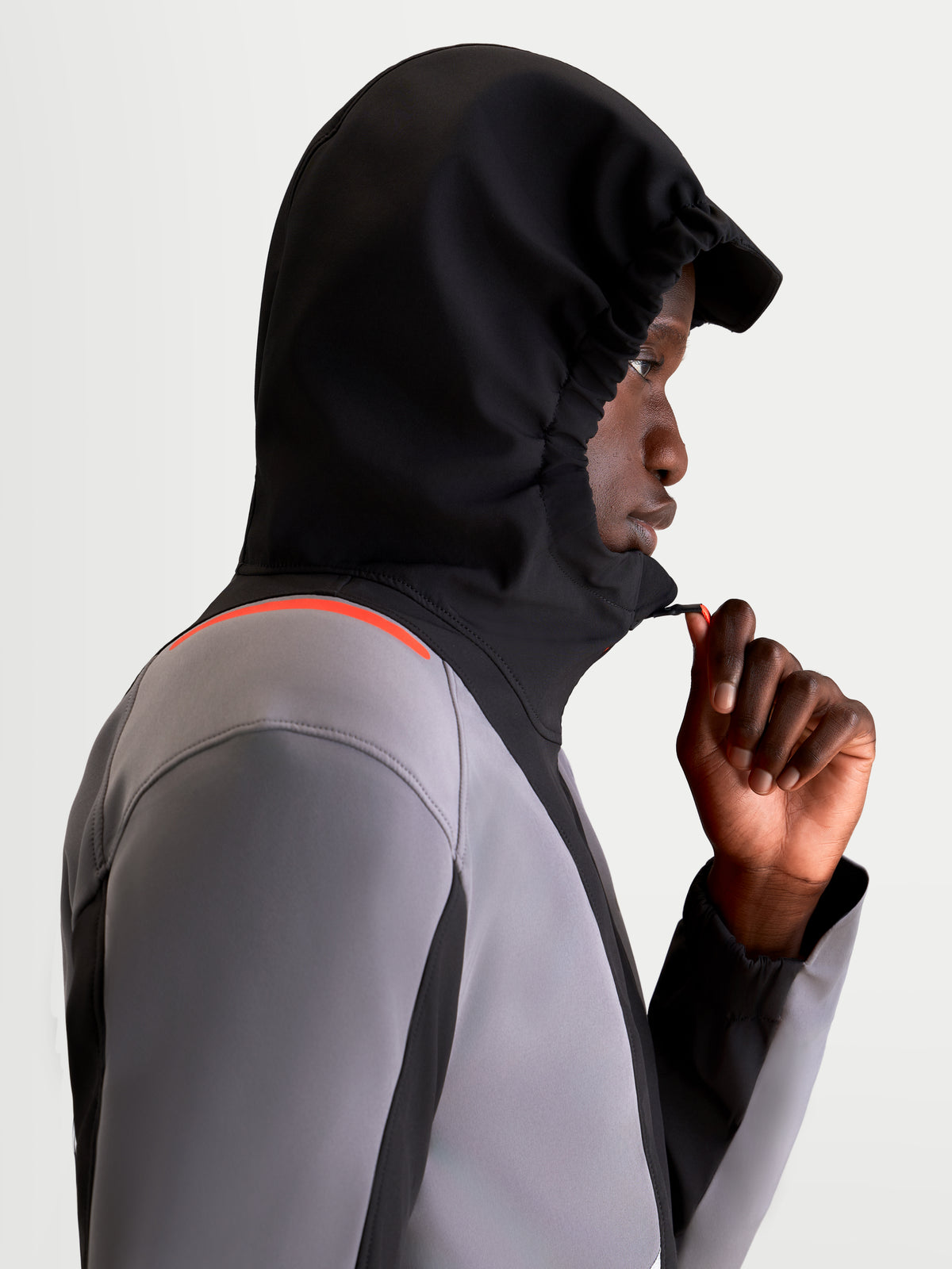 Alpinestars C 5 Drystar jas, heren urban motorjas van textiel in zwart en donkergrijs, zijaanzicht van een model dat de waterdichte jas draagt met de geïntegreerde capuchon op en de rits aan de voorkant verstelt