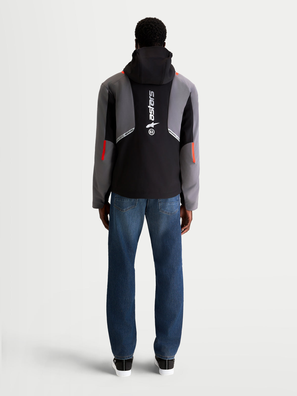 Alpinestars C 5 Drystar jas, heren urban motorjas in zwart en donkergrijs, achteraanzicht op een model met spijkerbroek, met geïntegreerde capuchon en groot verticaal logo op de rug