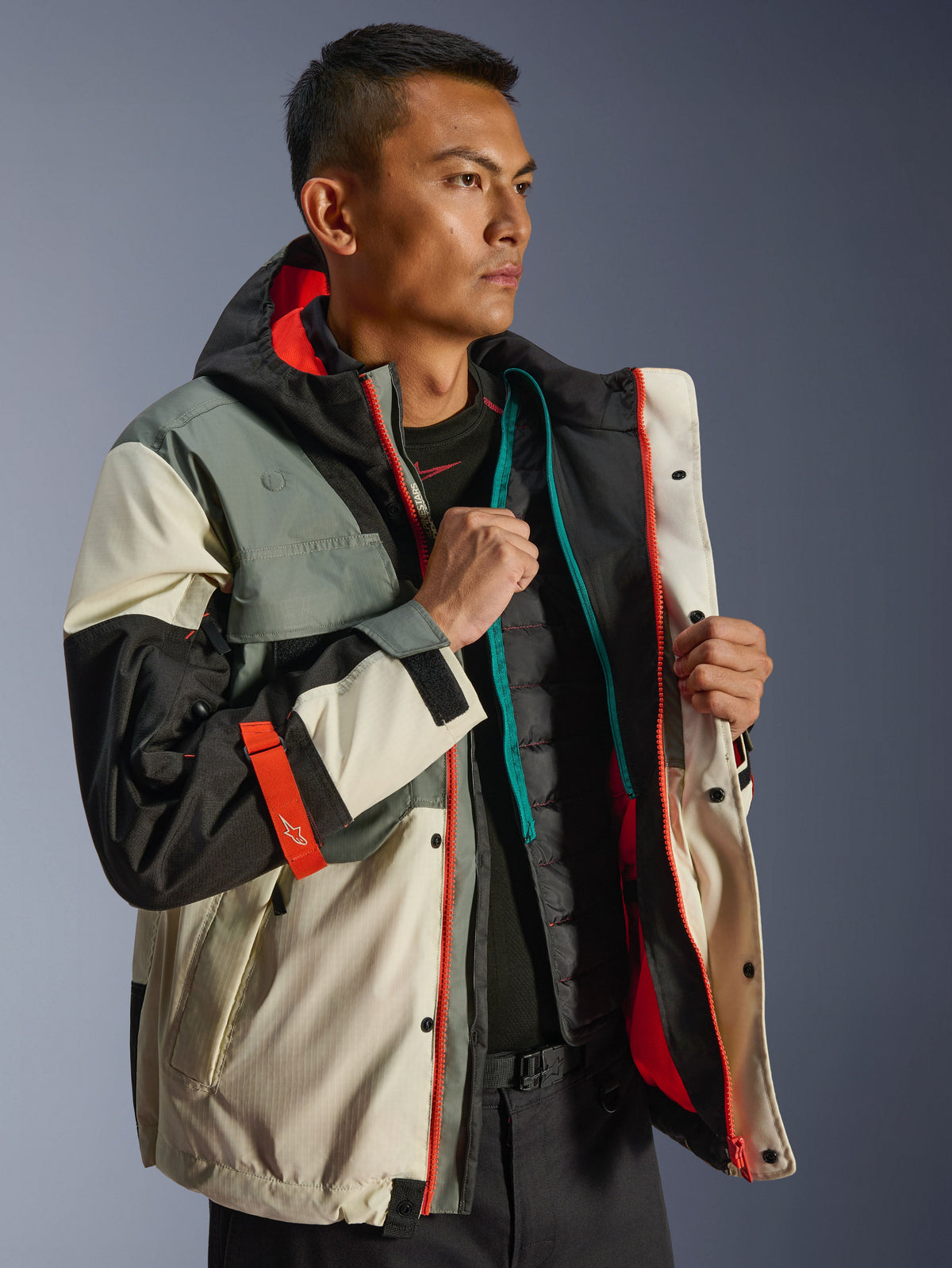 Alpinestars Mospher Waterproof Jacket, urban motorparka, Fur Gray Black Ice, met crème en grijze panelen en feloranje accenten, open gedragen met een gewatteerd thermisch vest, tactisch geïnspireerd ontwerp voor alle weersomstandigheden