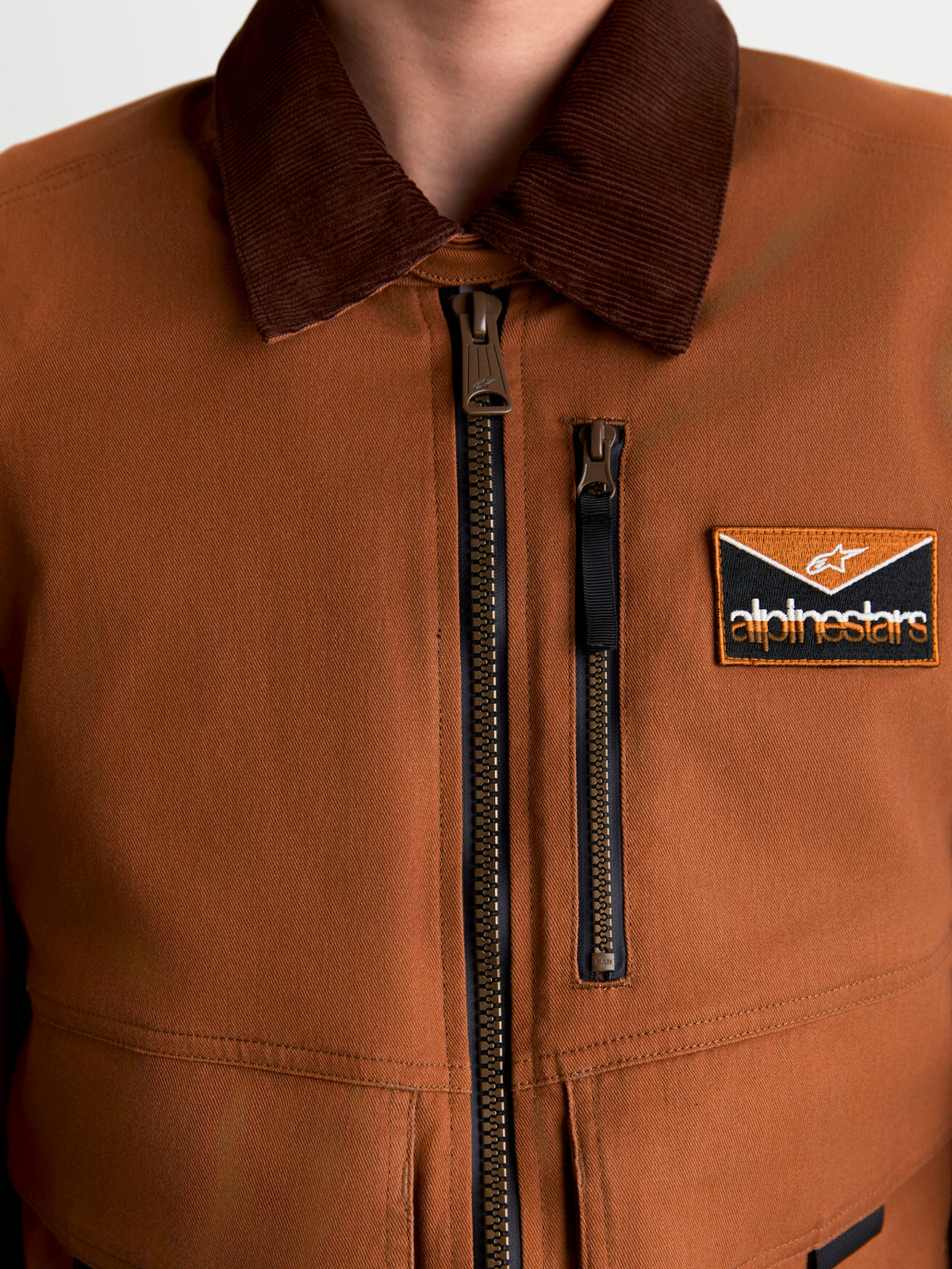 Alpinestars Mustang Wp jas, heren urban motorjas, donkerroestbruin en donkerbruin, detailopname van de workwear-stijl stretch twill constructie met corduroy kraag, rits aan de voorzijde en logopatch op de borst