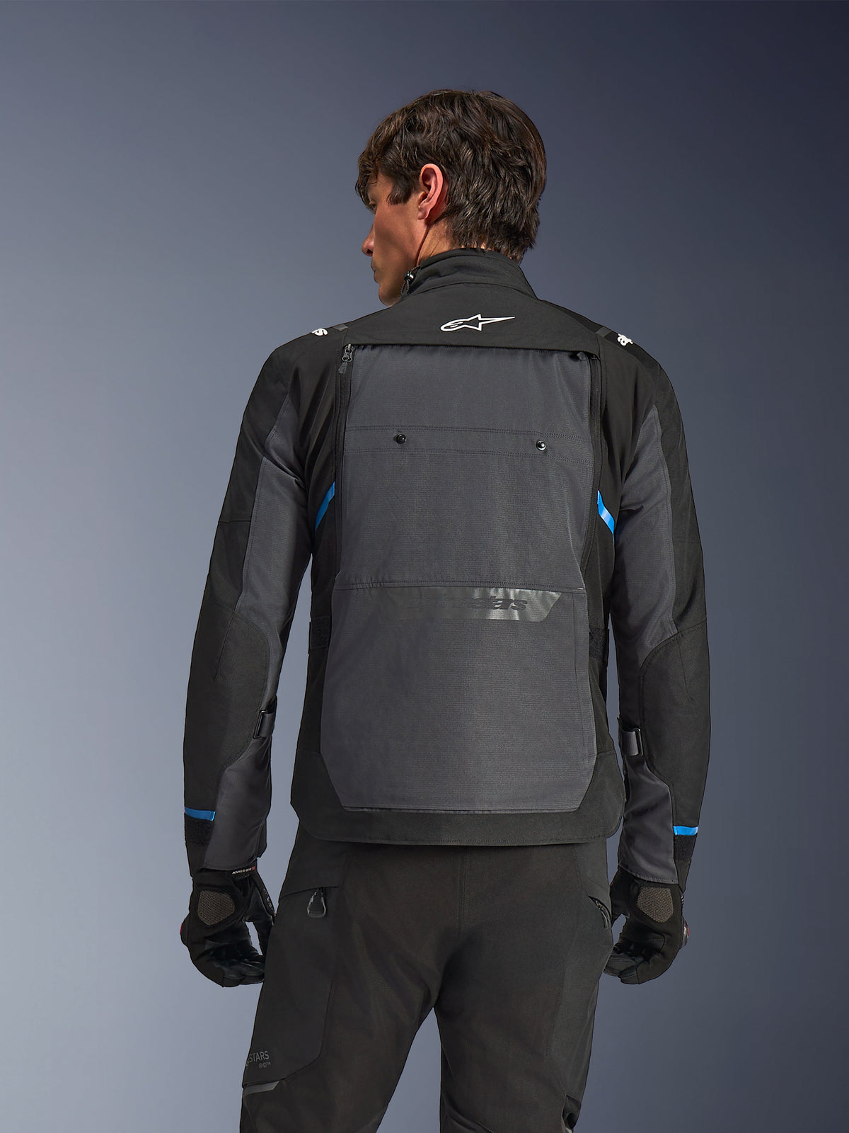 Alpinestars Cusco Drystar® Jacket, motorjas, zwart en diepgrijs, achteraanzicht op een model met groot grijs achterpaneel, wit Alpinestars-logo en blauwe accenten op de mouwen