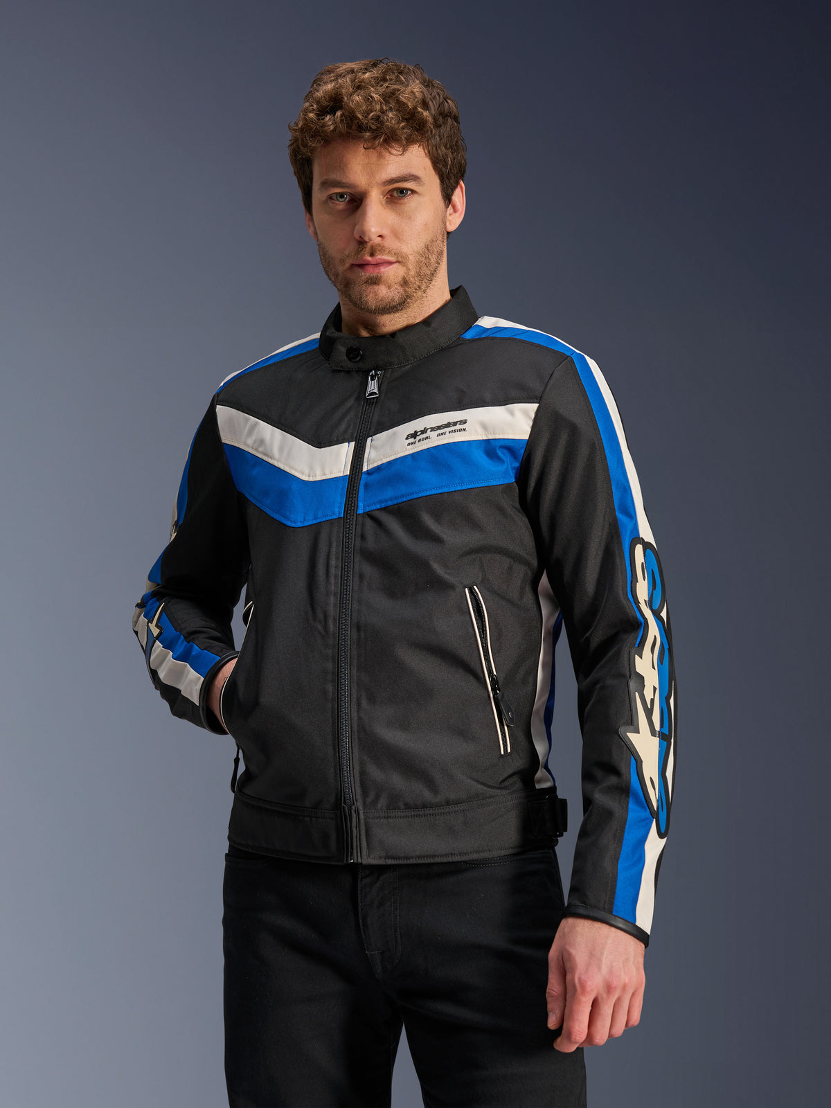 Alpinestars T-Dyno WR Jacket in Black Blue Ecru, textiele motorjas met blauwe en gebroken witte chevronstrepen op de borst en mouwen, gedragen door een model