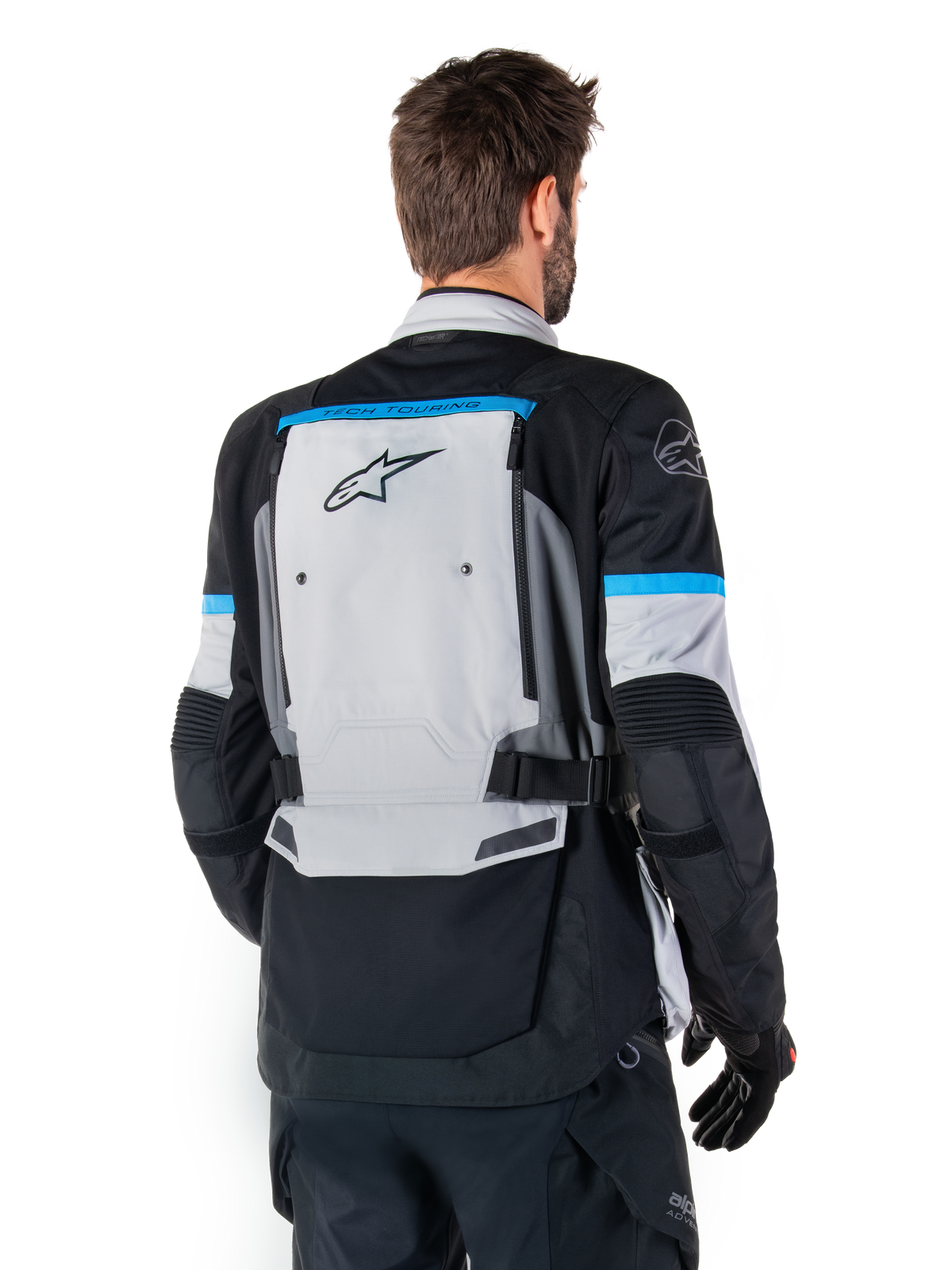 Alpinestars Bogota' Pro Drystar® Jas, adventure motorjas, ijsgrijs, zwart en cyaan, achteraanzicht met focus op het grote grijze rugpaneel met Tech Touring-branding, cyaan accenten op de mouwen en duurzame textielconstructie.
