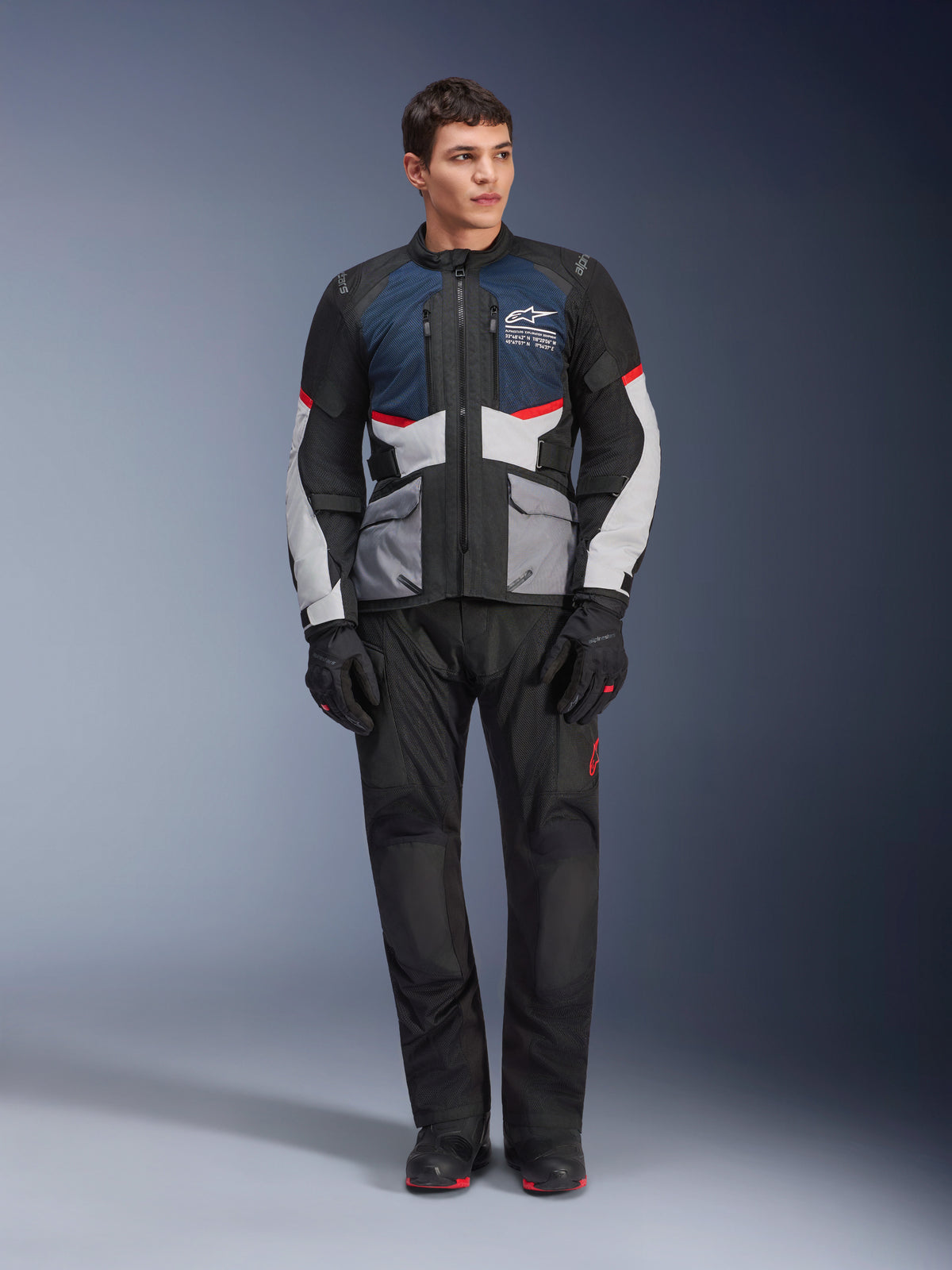 Alpinestars Andes Air Drystar® Jacket, Motorcycle Touring Jacket, Deep Blue Black and Ice Gray, worn with matching black adventure pants and gloves, featuring mesh panels for airflow and a technical multi-pocket design.